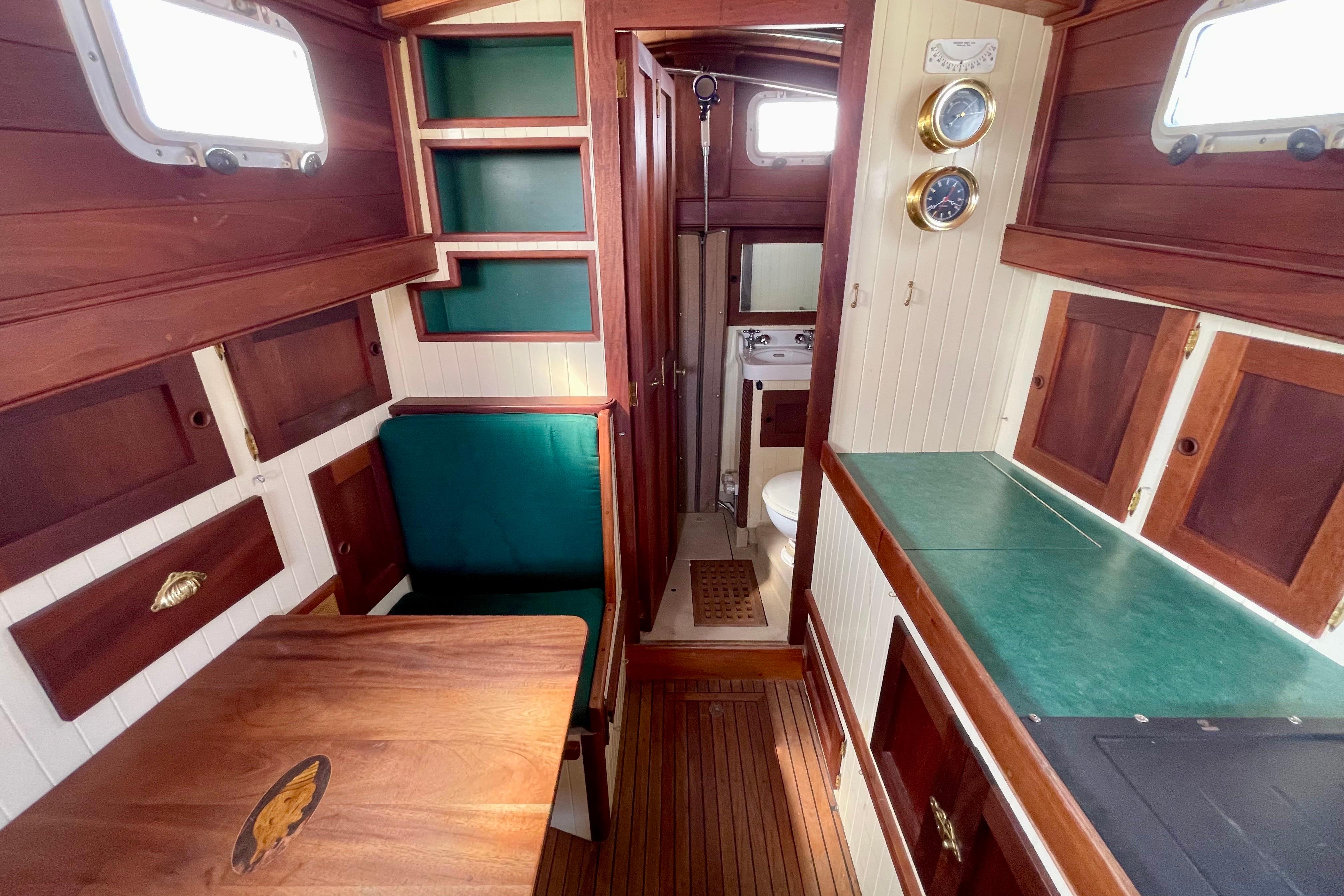 Cozy 2008 Pinky Custom boat interior with wood finish, dining area, and compact bathroom.
