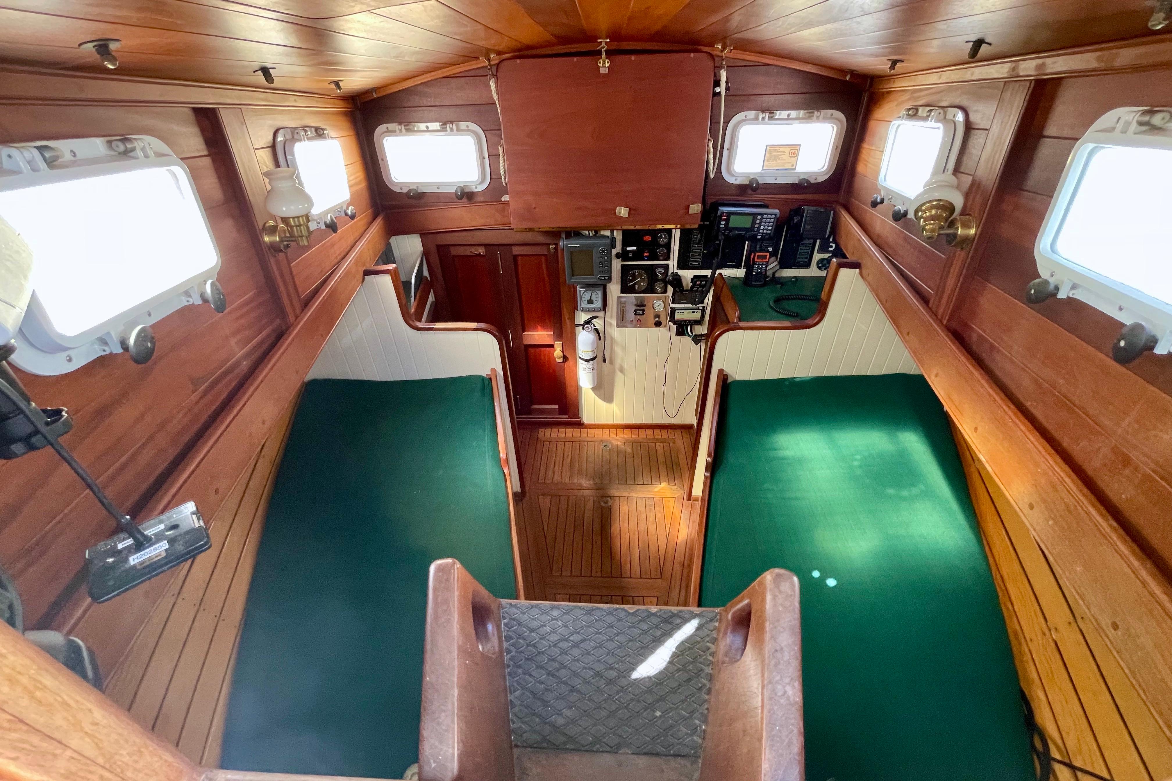 Interior of 2008 Pinky Custom boat with wooden paneling and green seating.