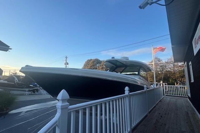 2024 Chris-Craft Calypso 35 boat docked near a white fence with American flag.