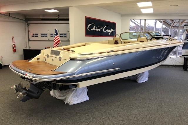 2026 Chris-Craft Launch 27 boat displayed indoors, featuring sleek design and American flag.