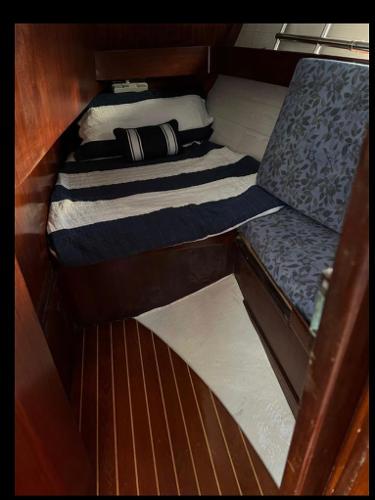 Cozy cabin interior of 1985 Gib'Sea 126 sailboat with striped bedding and wooden flooring.