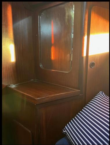Interior of 1985 Gib'Sea 126 sailboat with wooden cabinetry and striped cushion.