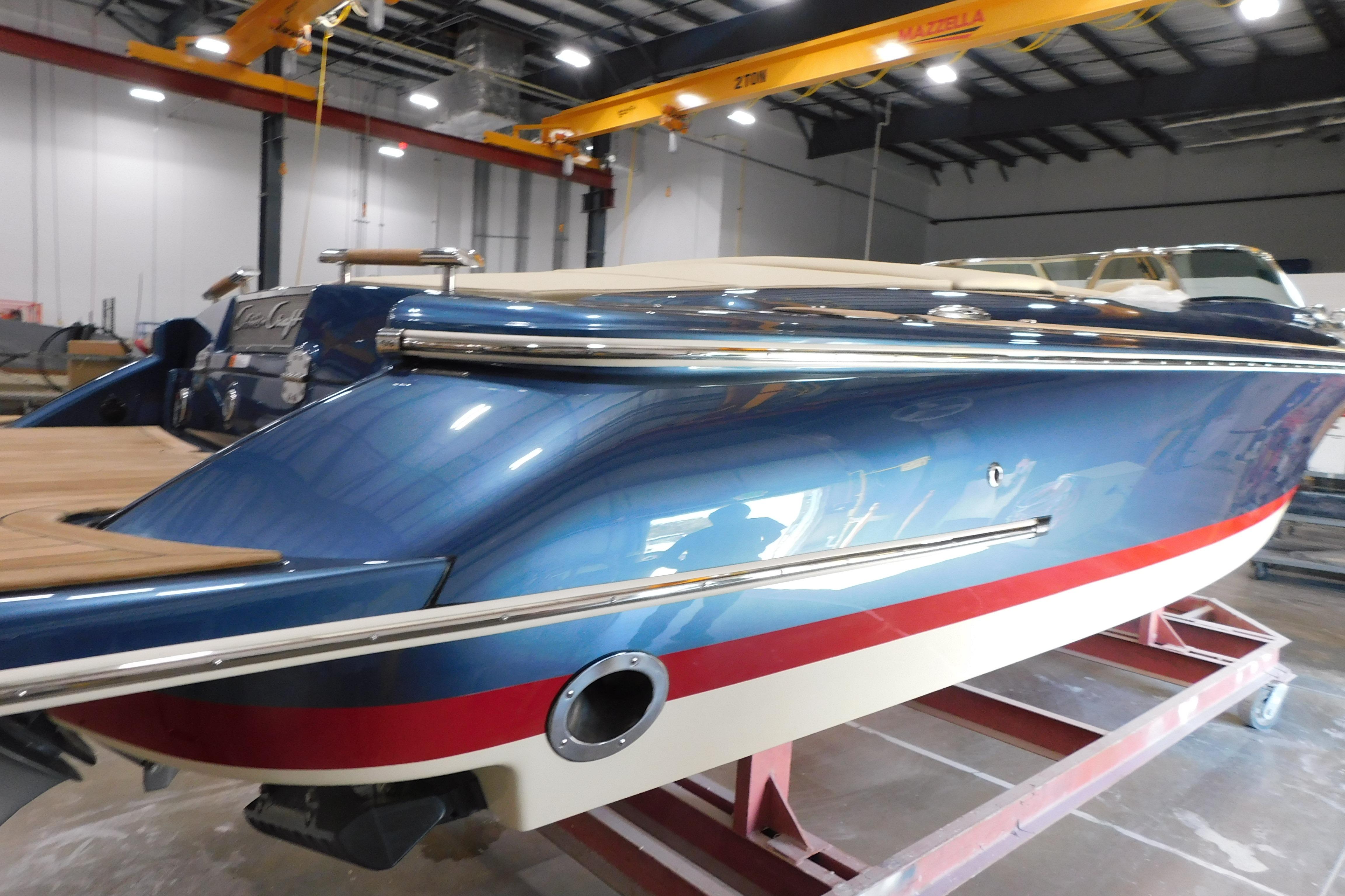 2025 Chris-Craft Launch 27 boat in a showroom, featuring sleek blue and red design.