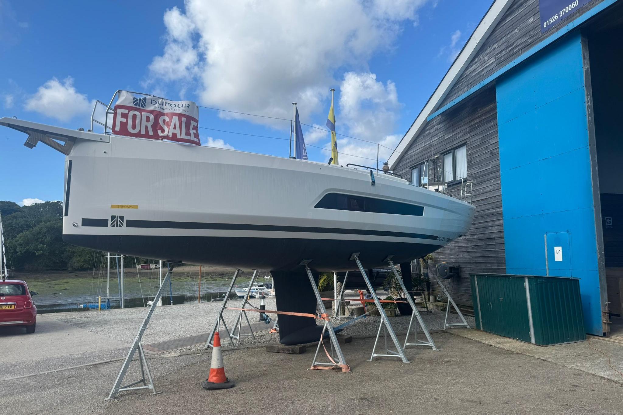 2025 Dufour 37 yacht for sale, elevated on stands near a blue building.