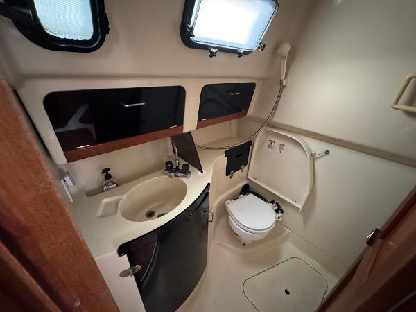 Compact bathroom in a 1994 Hunter 29.5 sailboat, featuring sink, toilet, and storage cabinets.