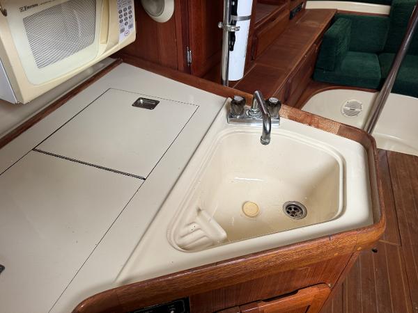 1994 Hunter 29.5 yacht kitchen with sink, microwave, and wooden cabinetry.