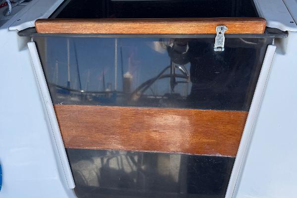 Wooden hatch door on a 1994 Hunter 29.5 sailboat, with marina reflections.