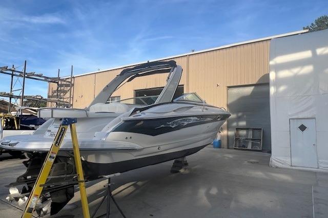 2007 Crownline 320 LS boat on dry dock outside a warehouse under clear blue sky.