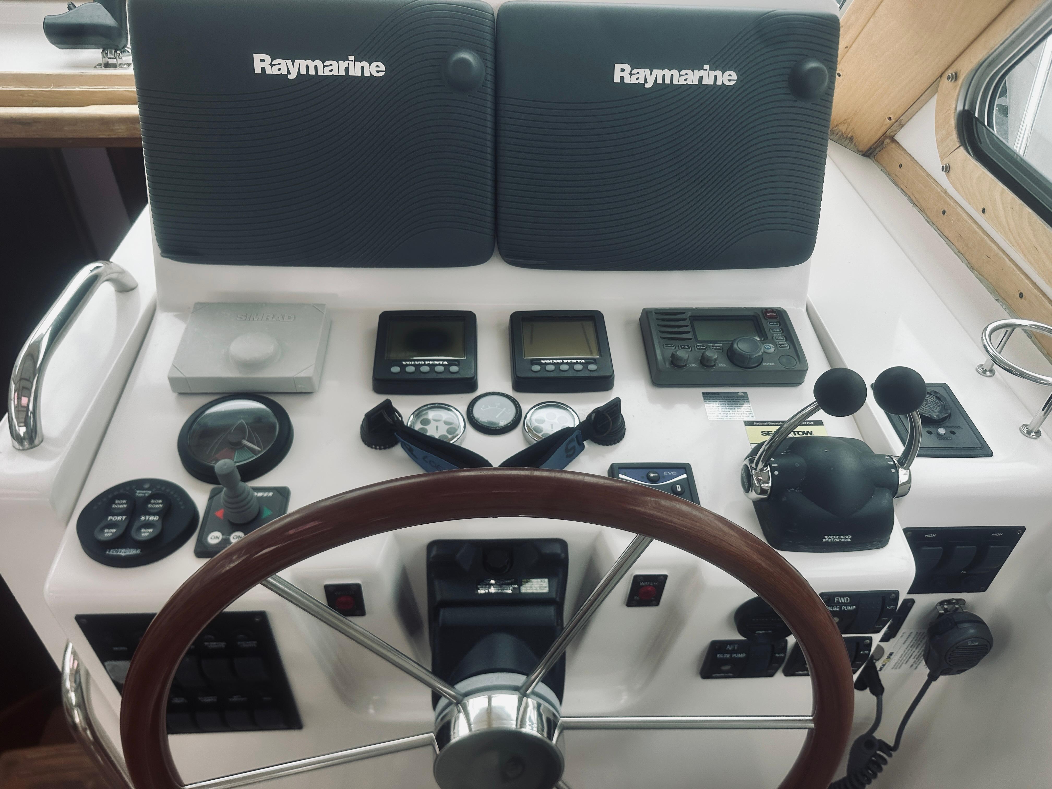 2007 Sabreline 34 Express helm with Raymarine navigation equipment and wooden steering wheel.