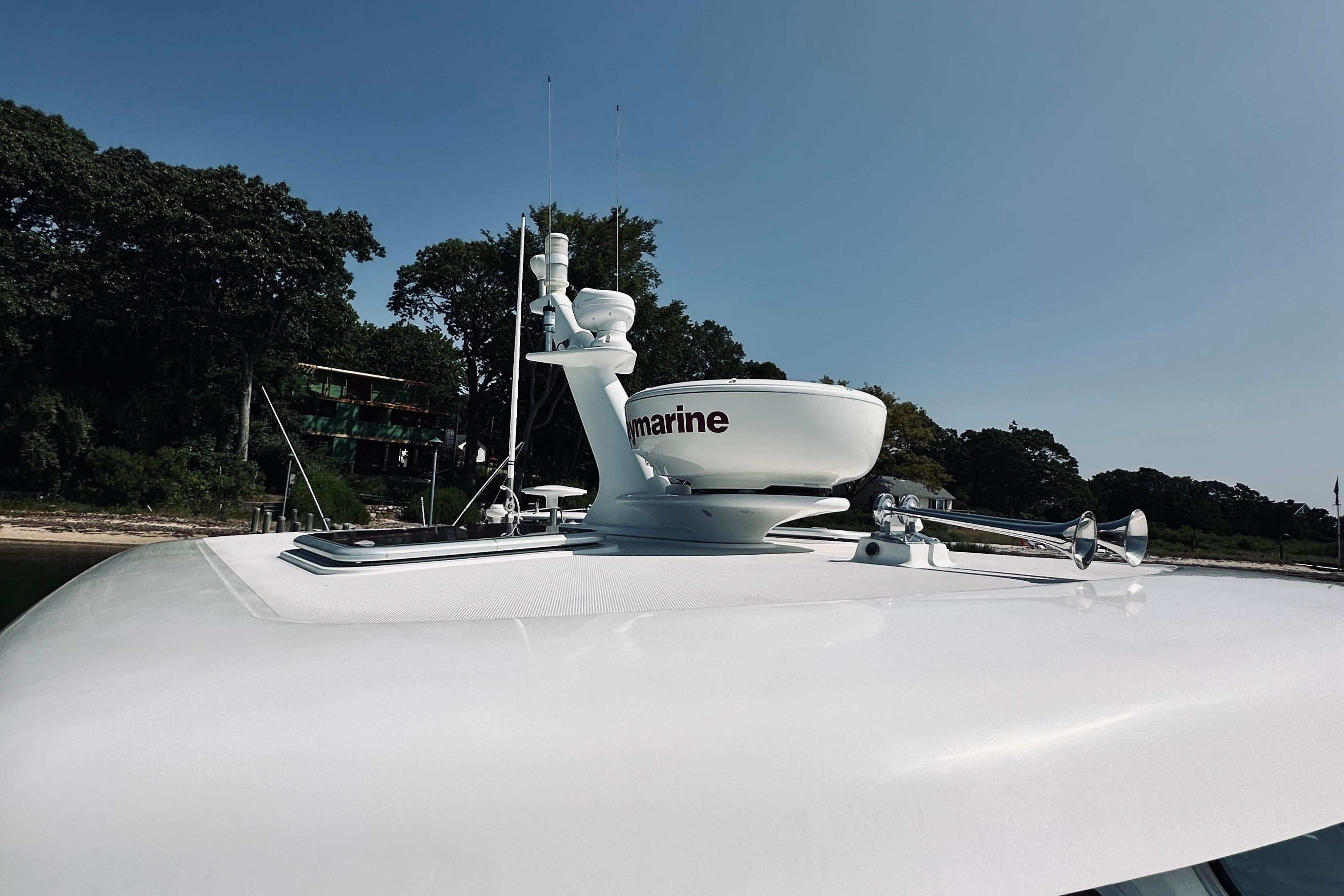 2007 Sabreline 34 Express yacht with radar equipment, docked near a wooded shoreline.