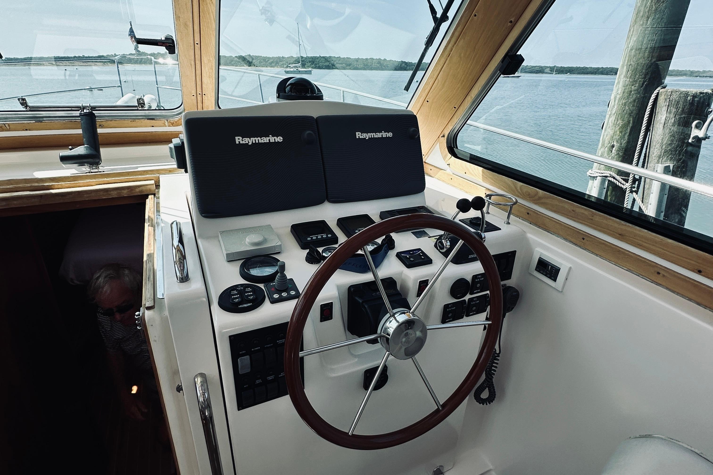 2007 Sabreline 34 Express helm with Raymarine electronics, wooden steering wheel, and scenic water view.