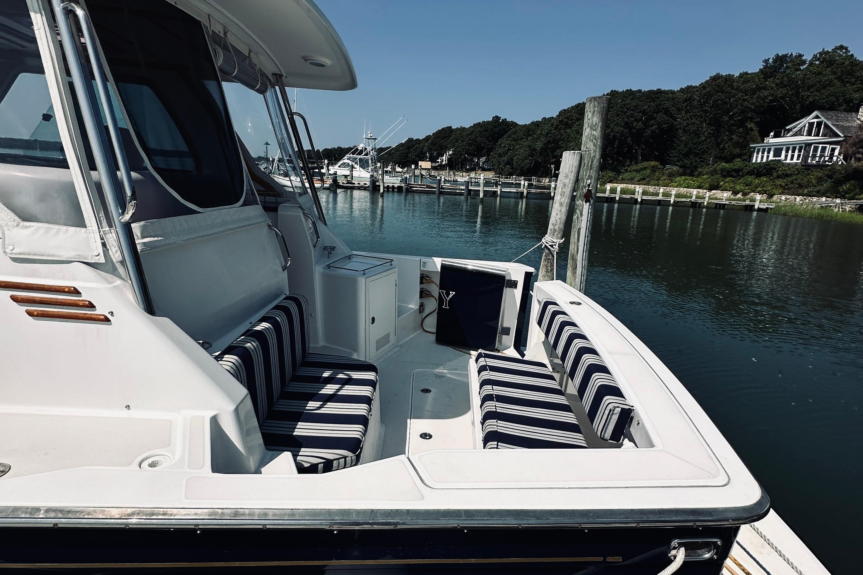 2007 Sabreline 34 Express boat docked, featuring striped seating and scenic waterfront view.