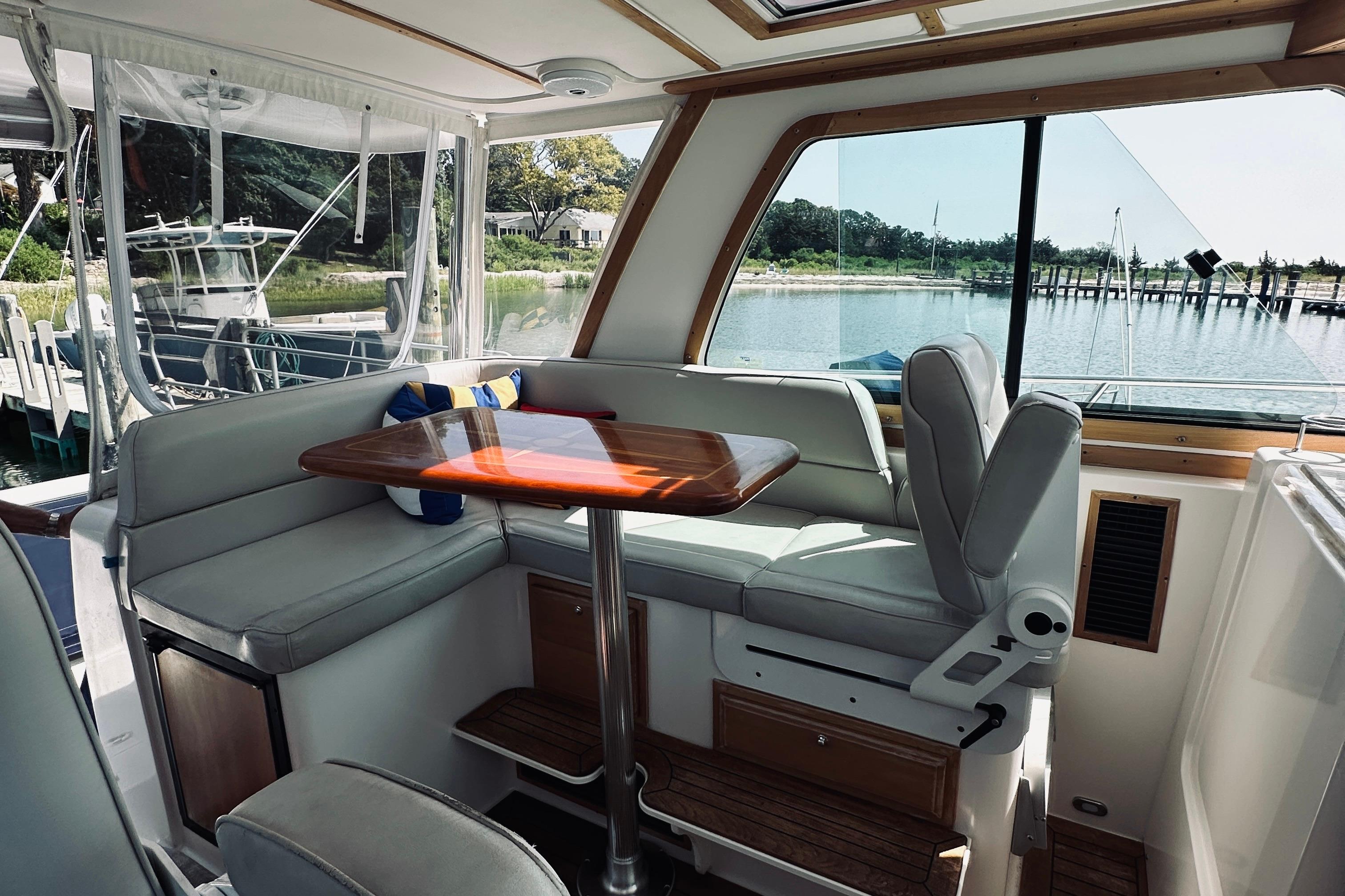 Interior of 2007 Sabreline 34 Express yacht with seating and table, overlooking marina.
