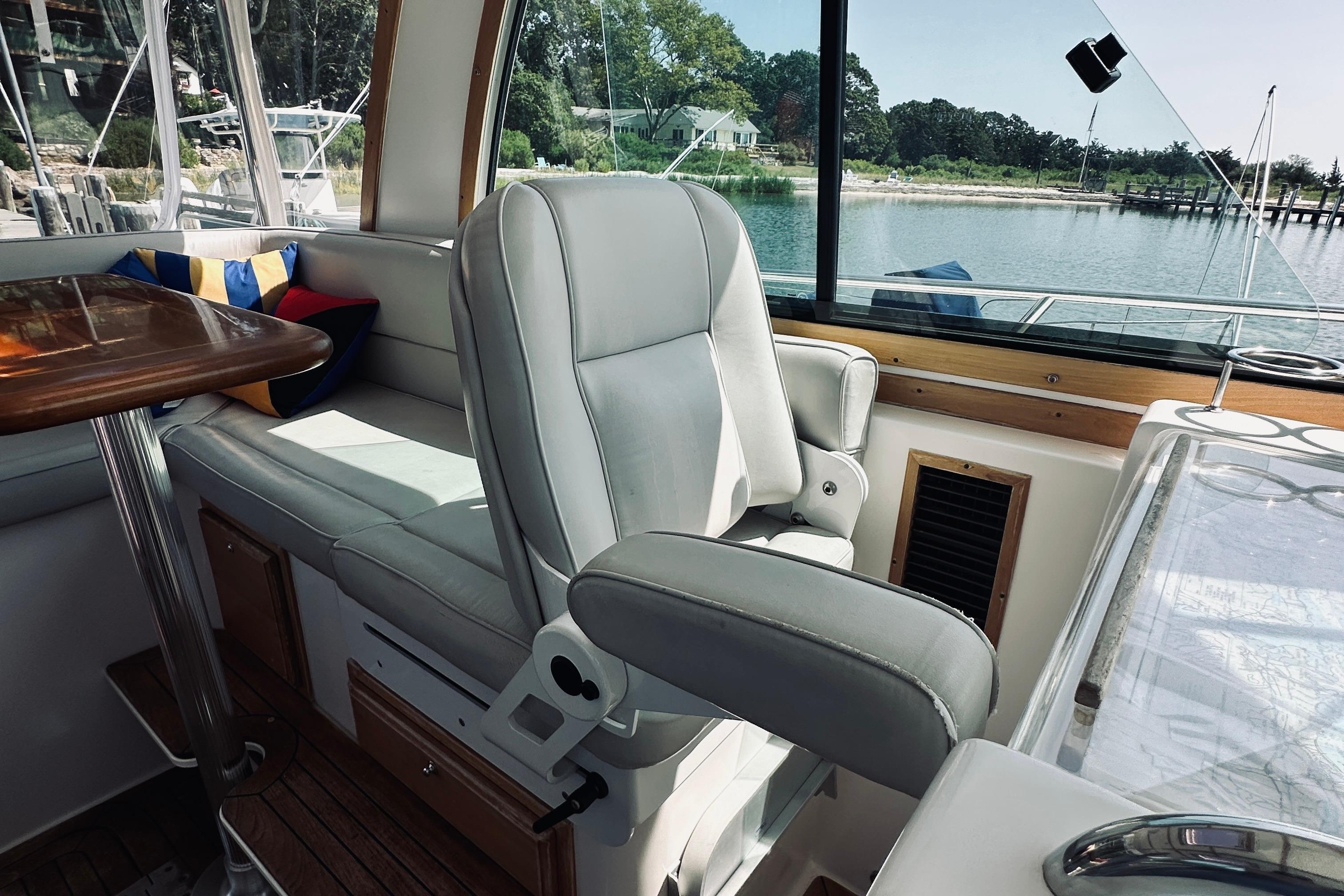 2007 Sabreline 34 Express interior with helm seat and table, overlooking serene waterfront.