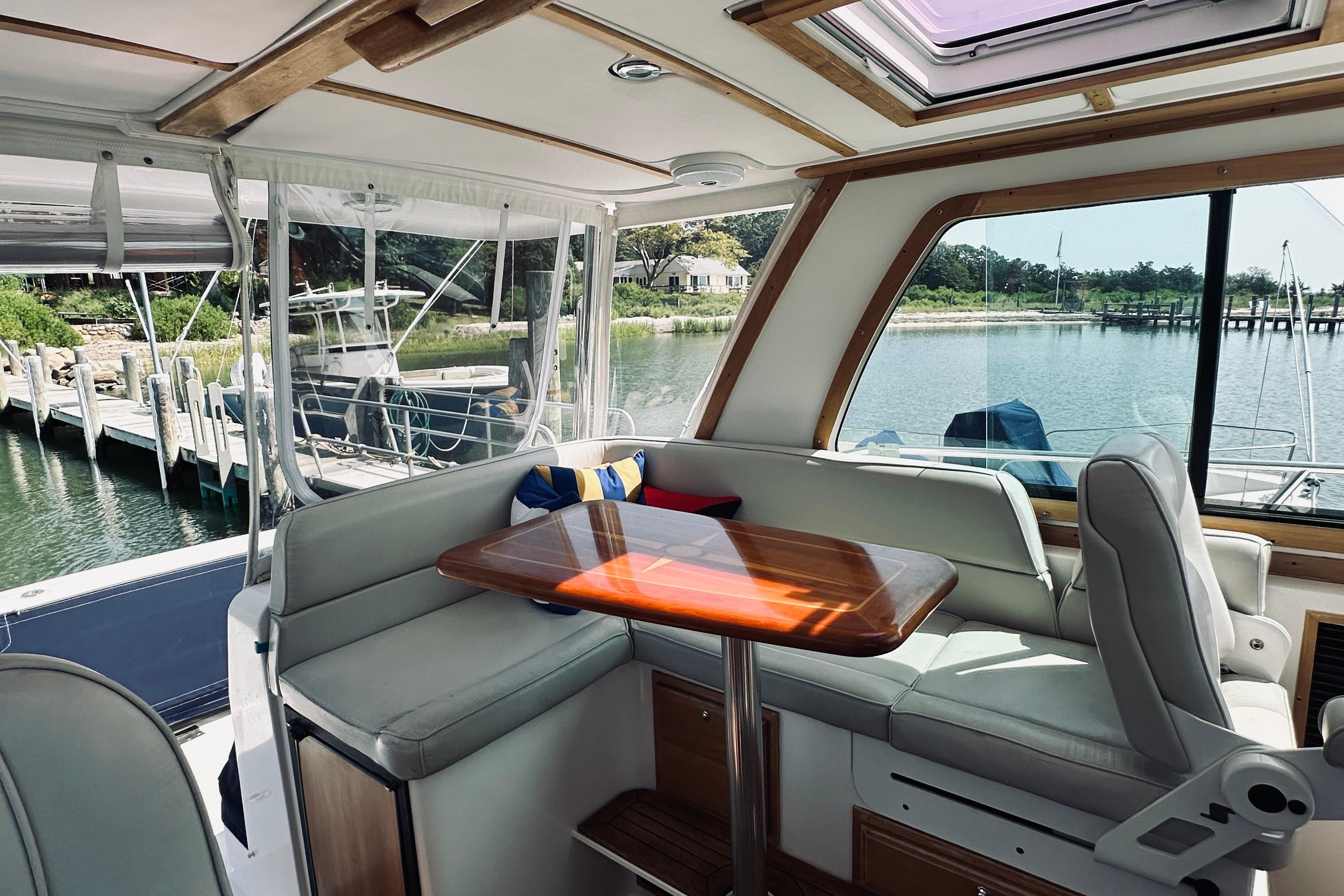 Interior of 2007 Sabreline 34 Express yacht with seating and table, docked by water.