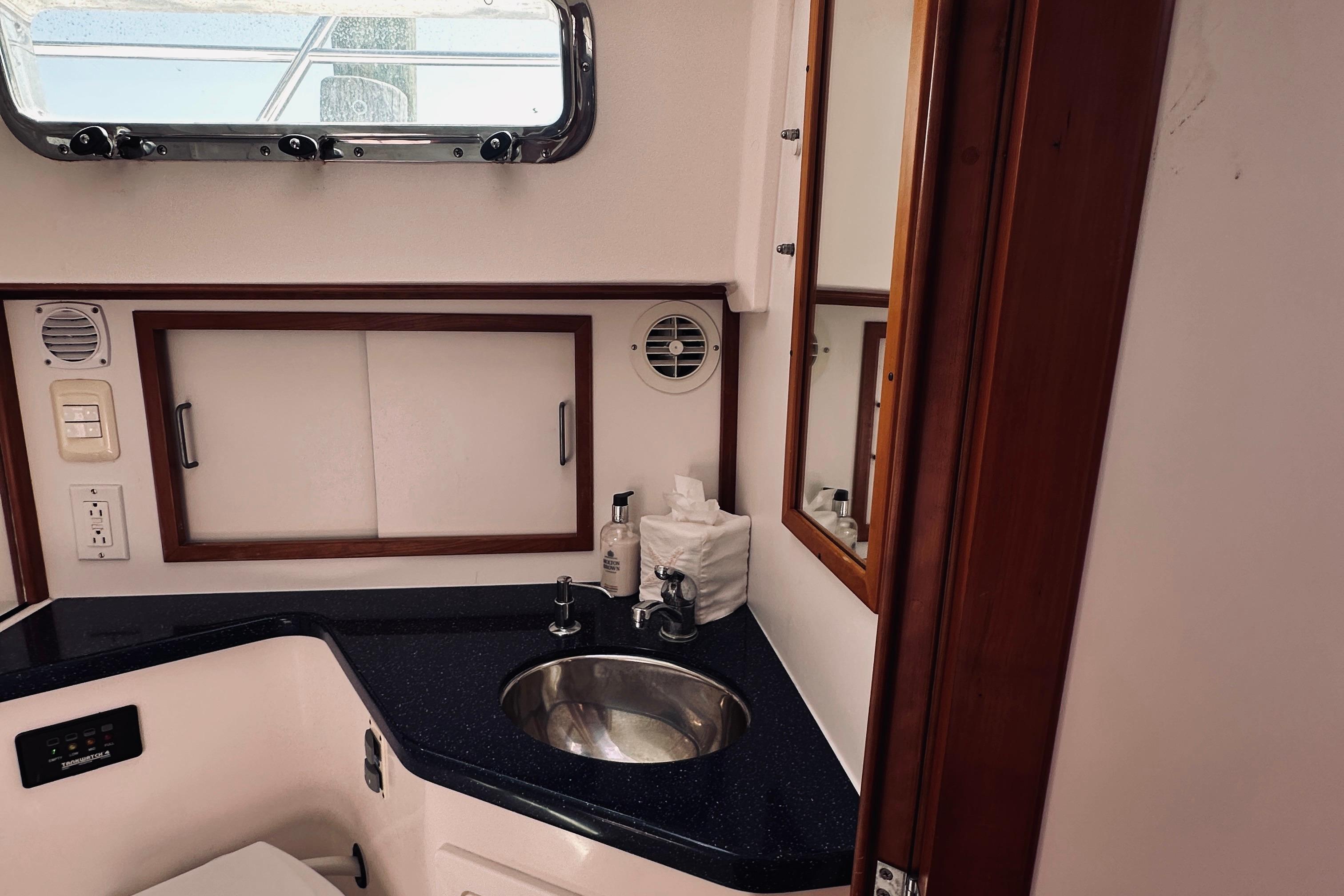 2007 Sabreline 34 Express yacht bathroom with sink, mirror, and storage cabinets.