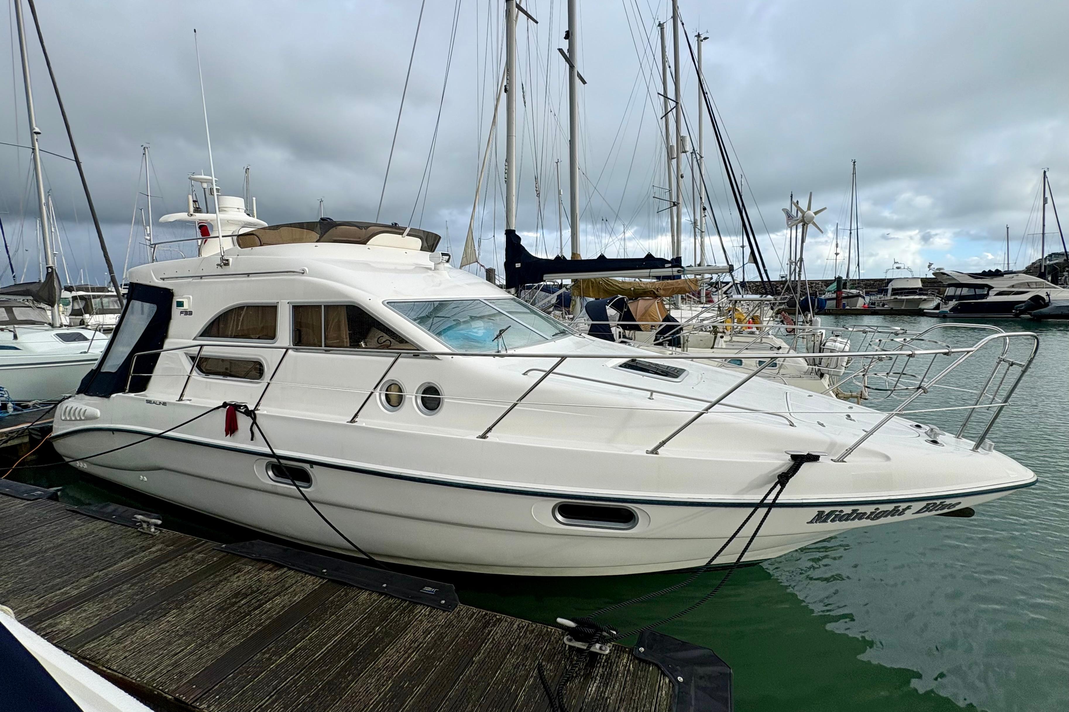 2001 Sealine F33 yacht docked at marina under cloudy skies.