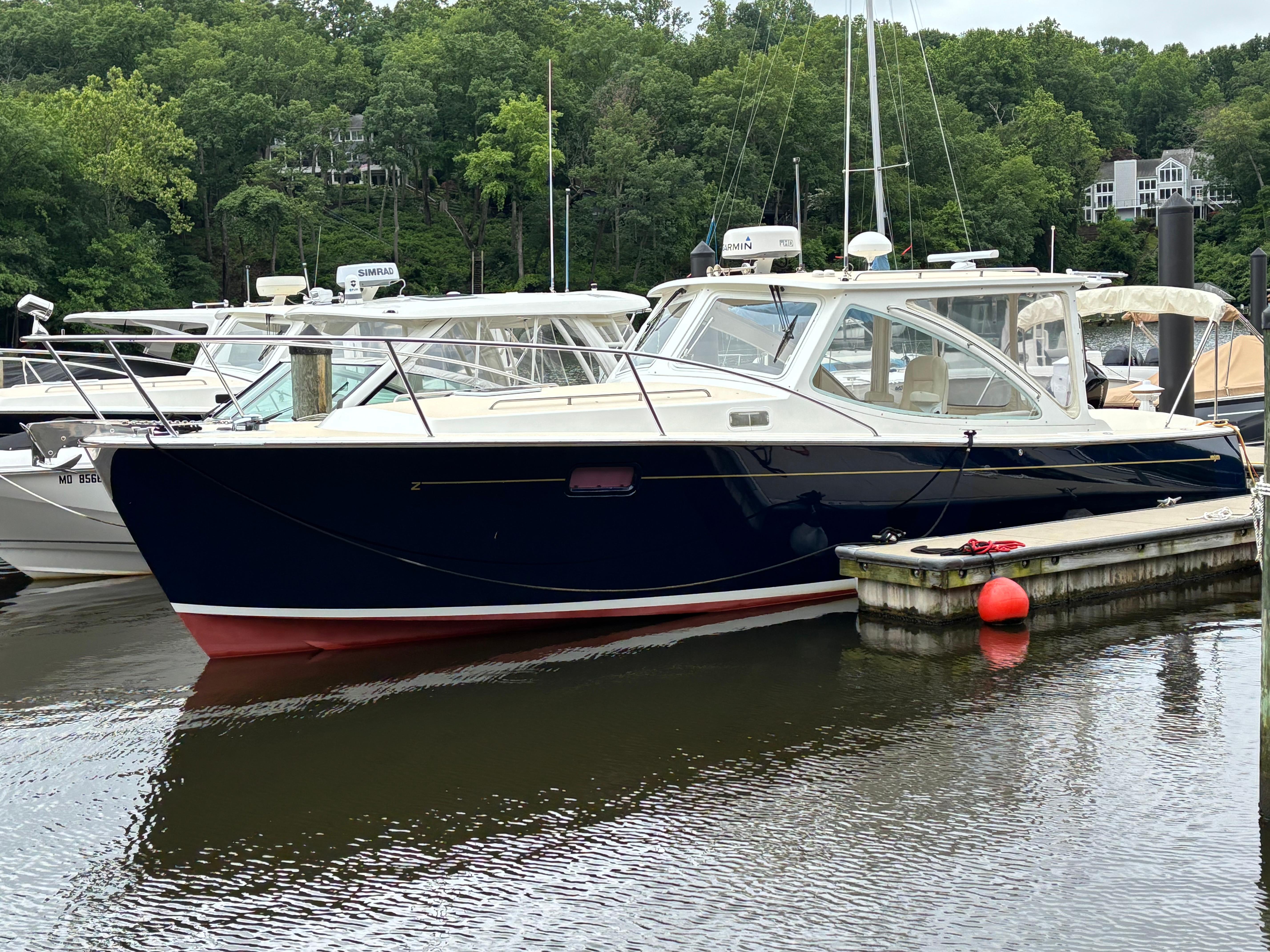MJM-34z Express HT 2006-Zest MD-US-2006 MJM 34z Express HT boat docked in a marina, surrounded by lush greenery.-9817750
