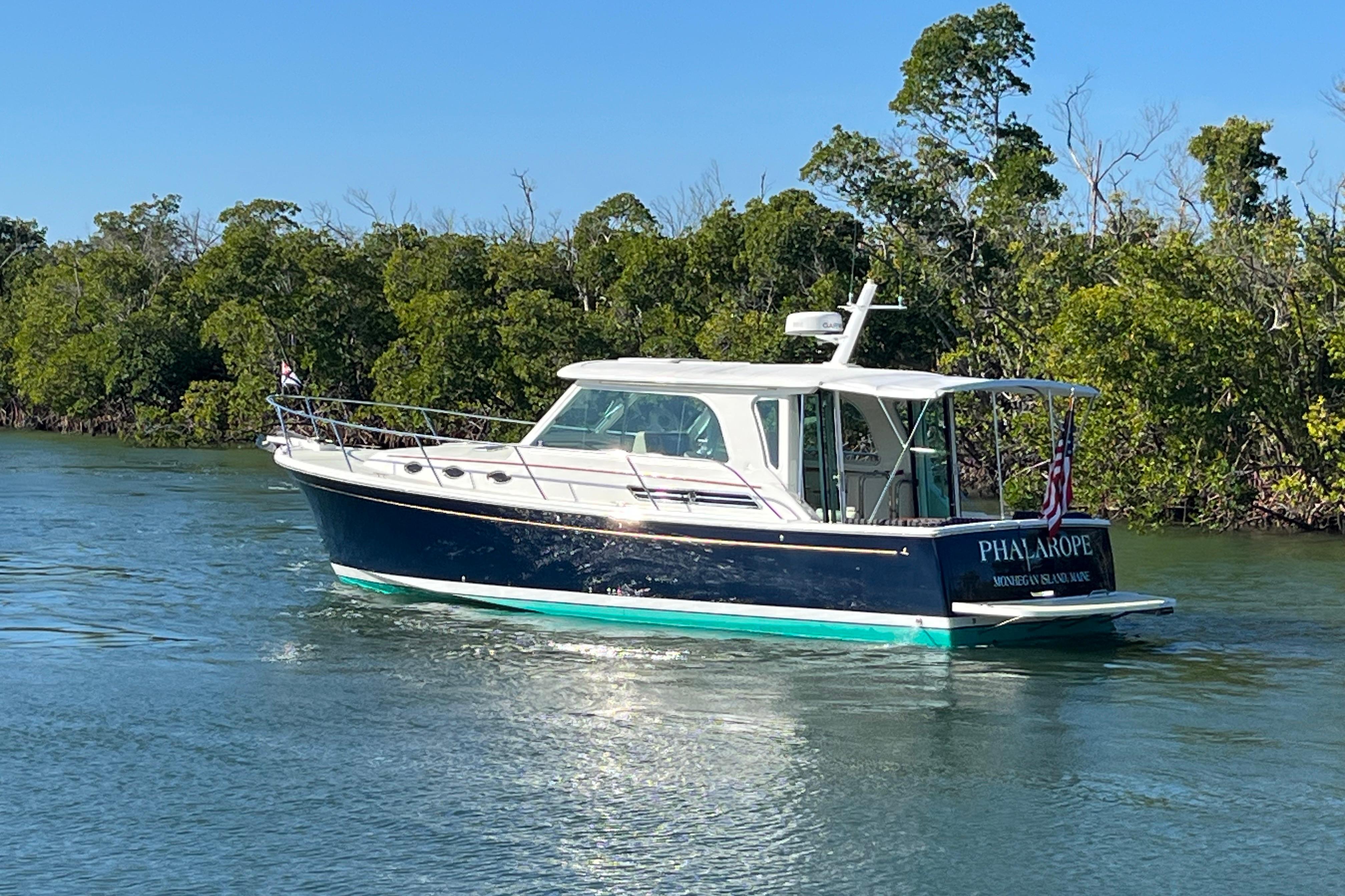 2017 Back Cove 37 boat cruising on a sunny day near lush greenery.
