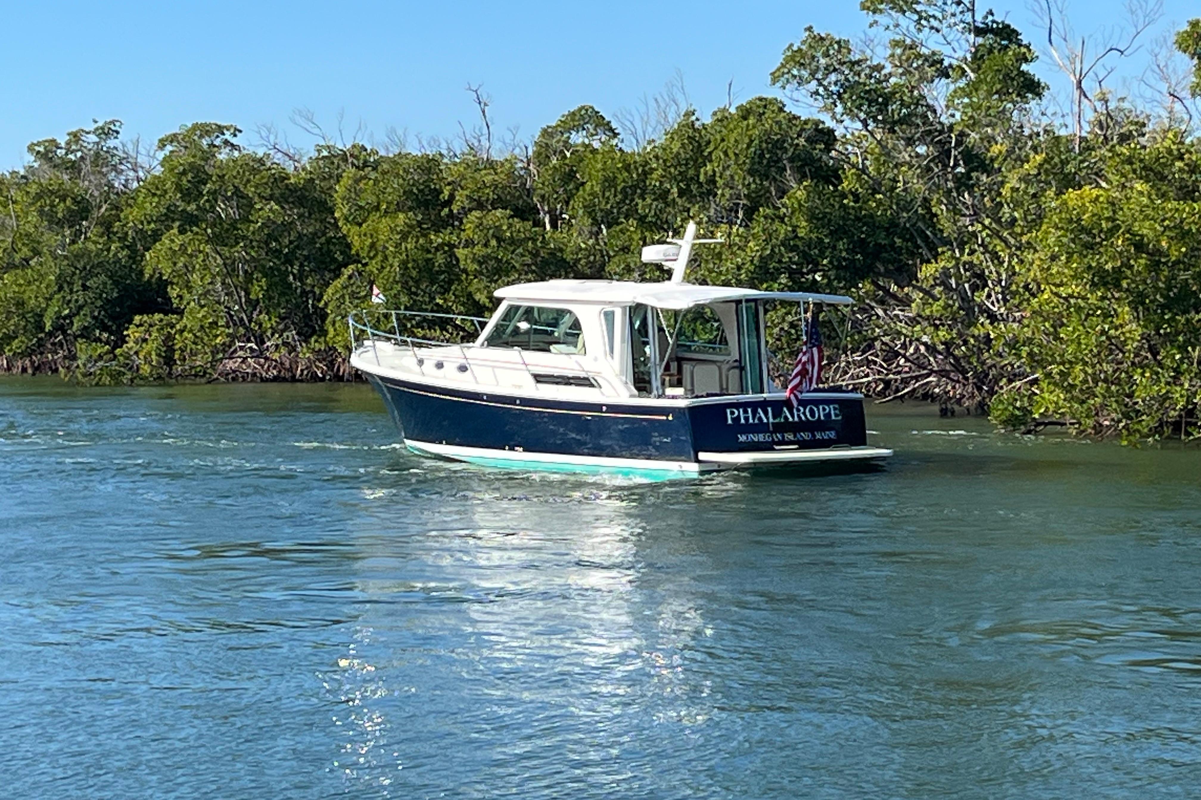 2017 Back Cove 37 boat cruising on a scenic waterway surrounded by lush greenery.
