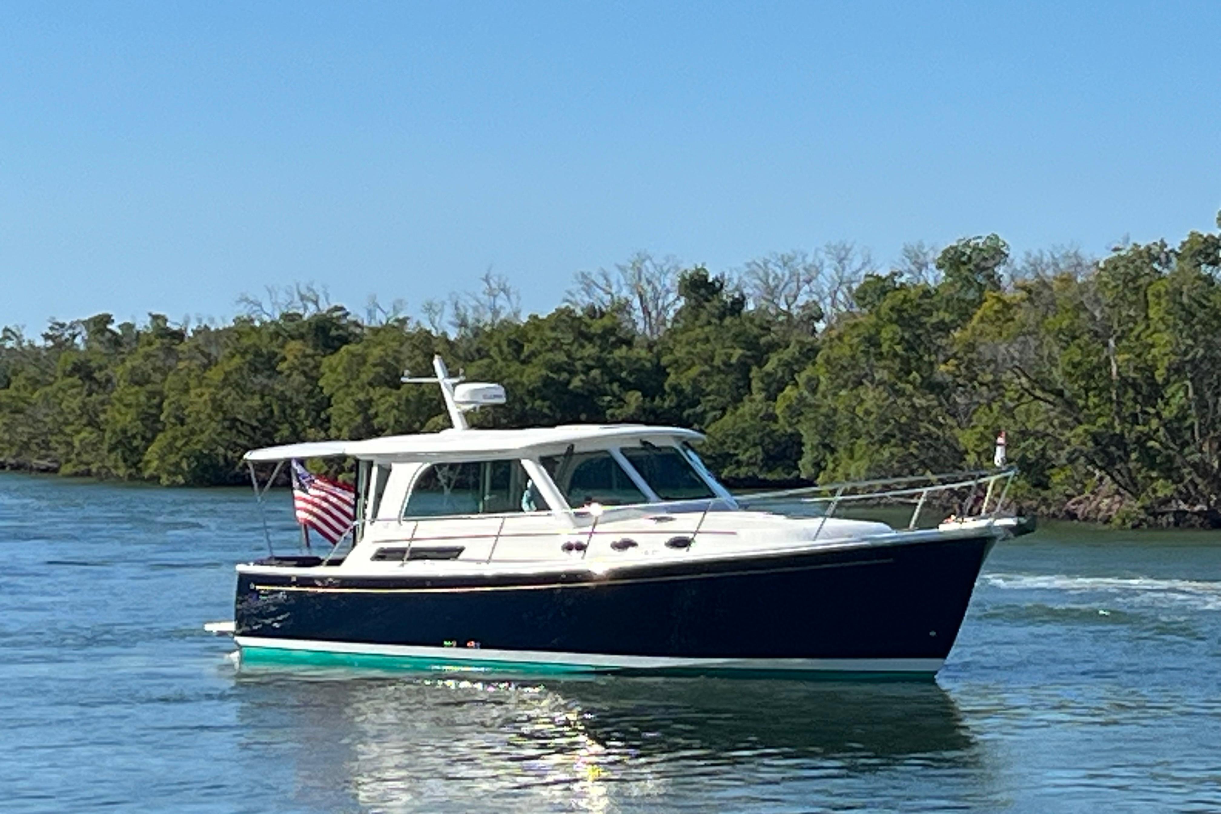 2017 Back Cove 37 boat cruising on a calm river with lush green trees.