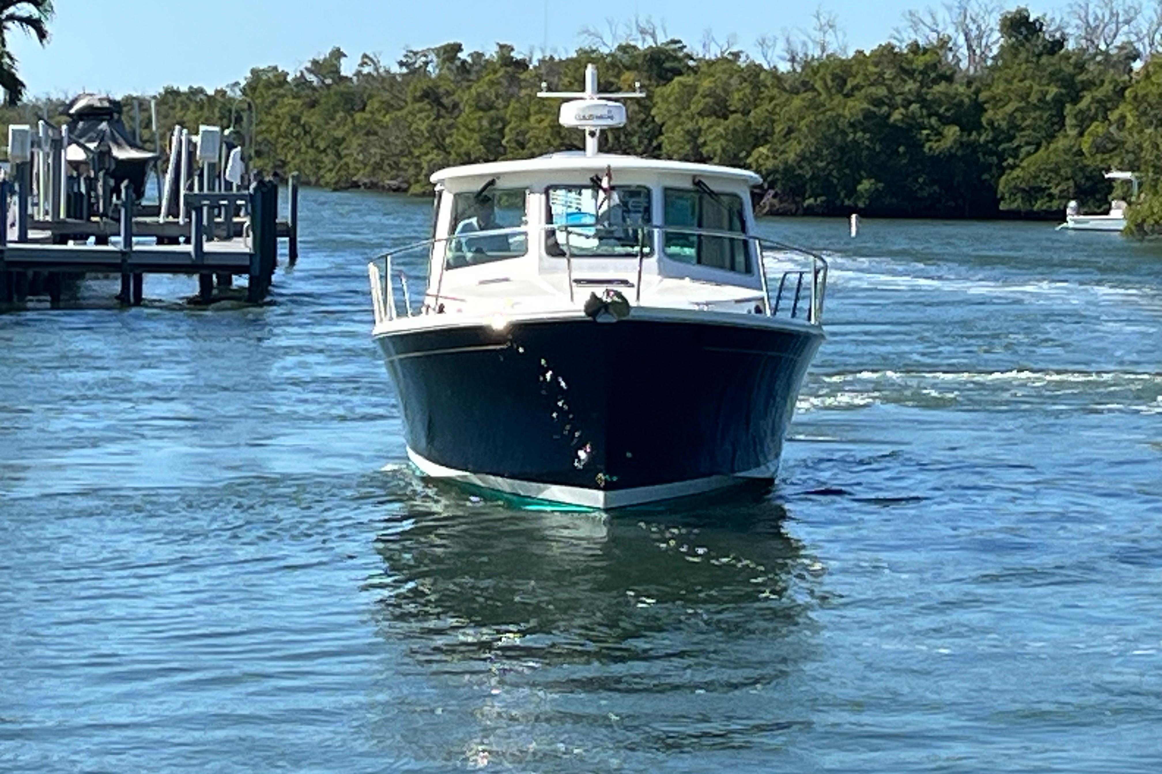 2017 Back Cove 37 boat navigating through calm waters near a dock.