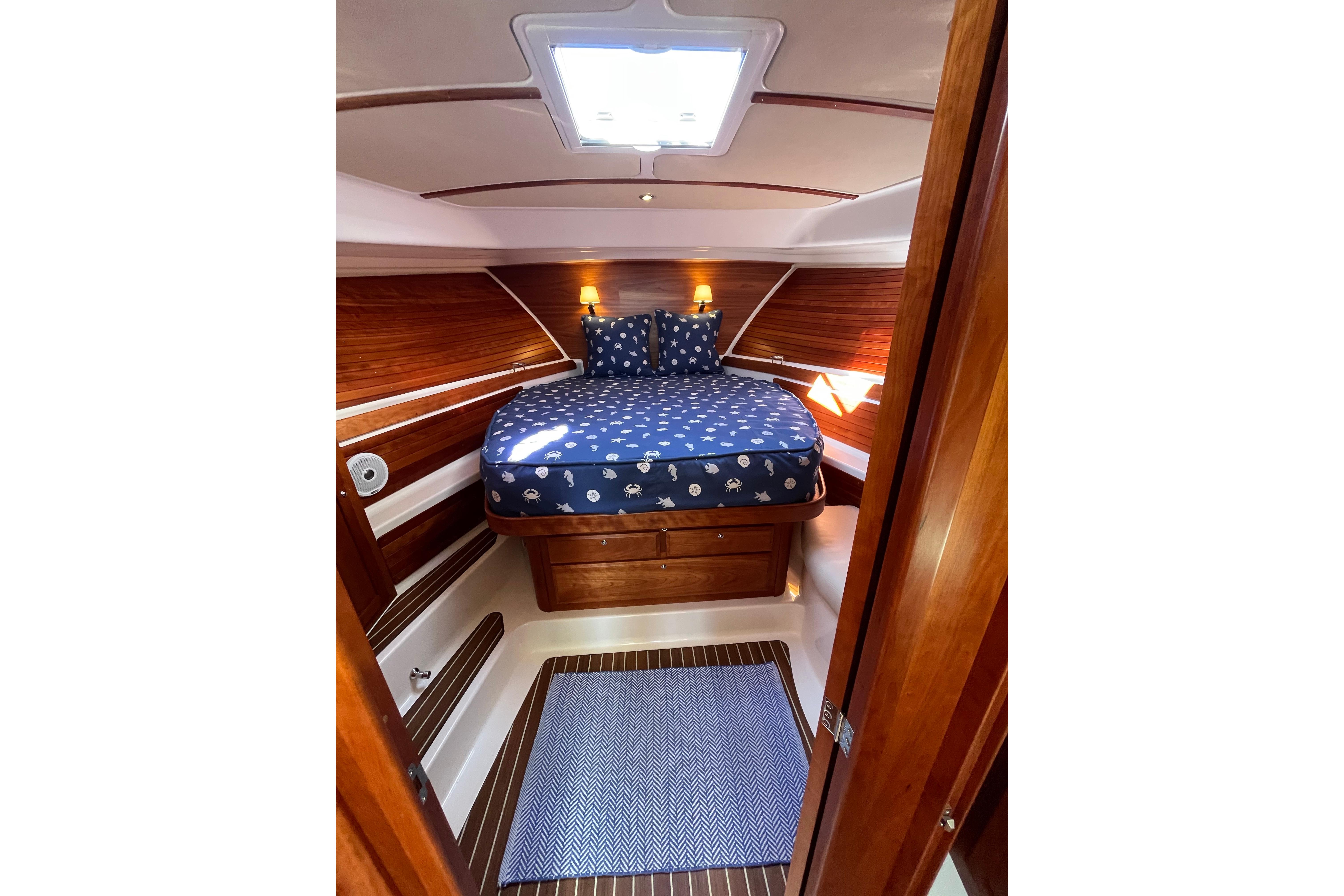 Cozy cabin interior of 2017 Back Cove 37 yacht with wooden accents and nautical bedding.