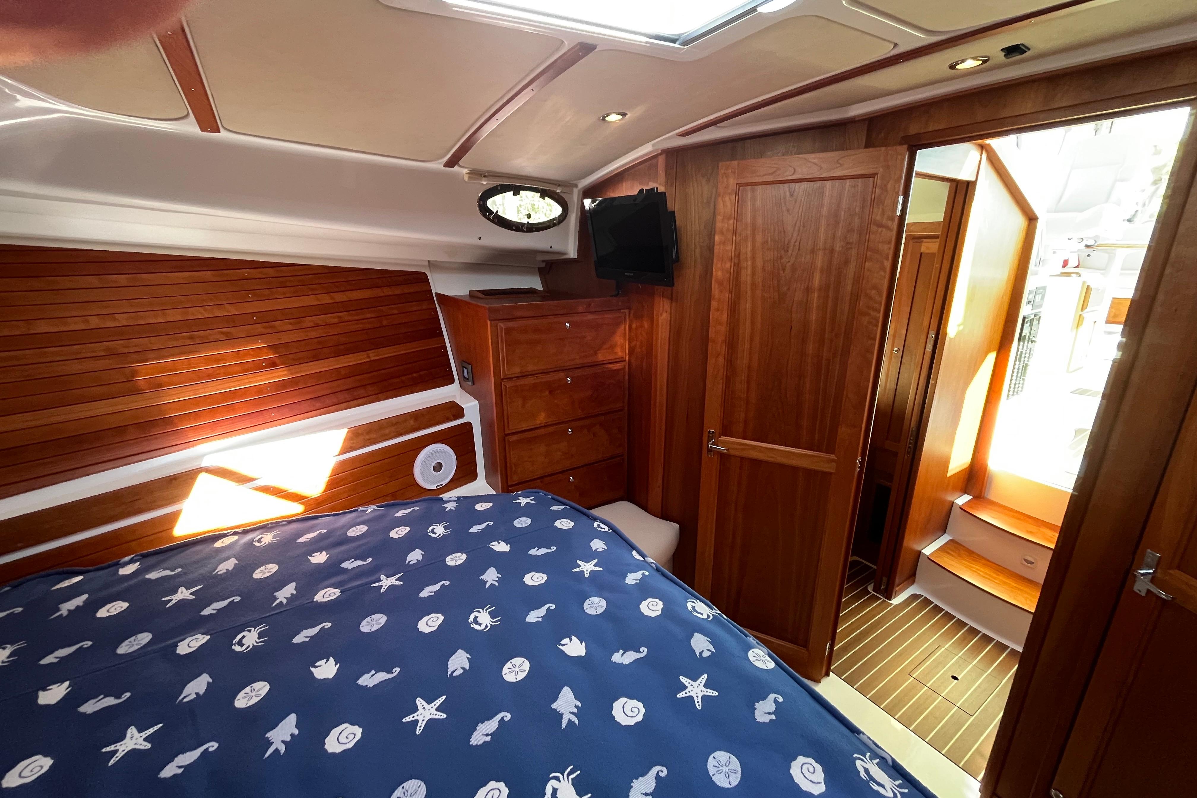 Luxurious cabin interior of 2017 Back Cove 37 yacht with wooden finishes and nautical bedding.