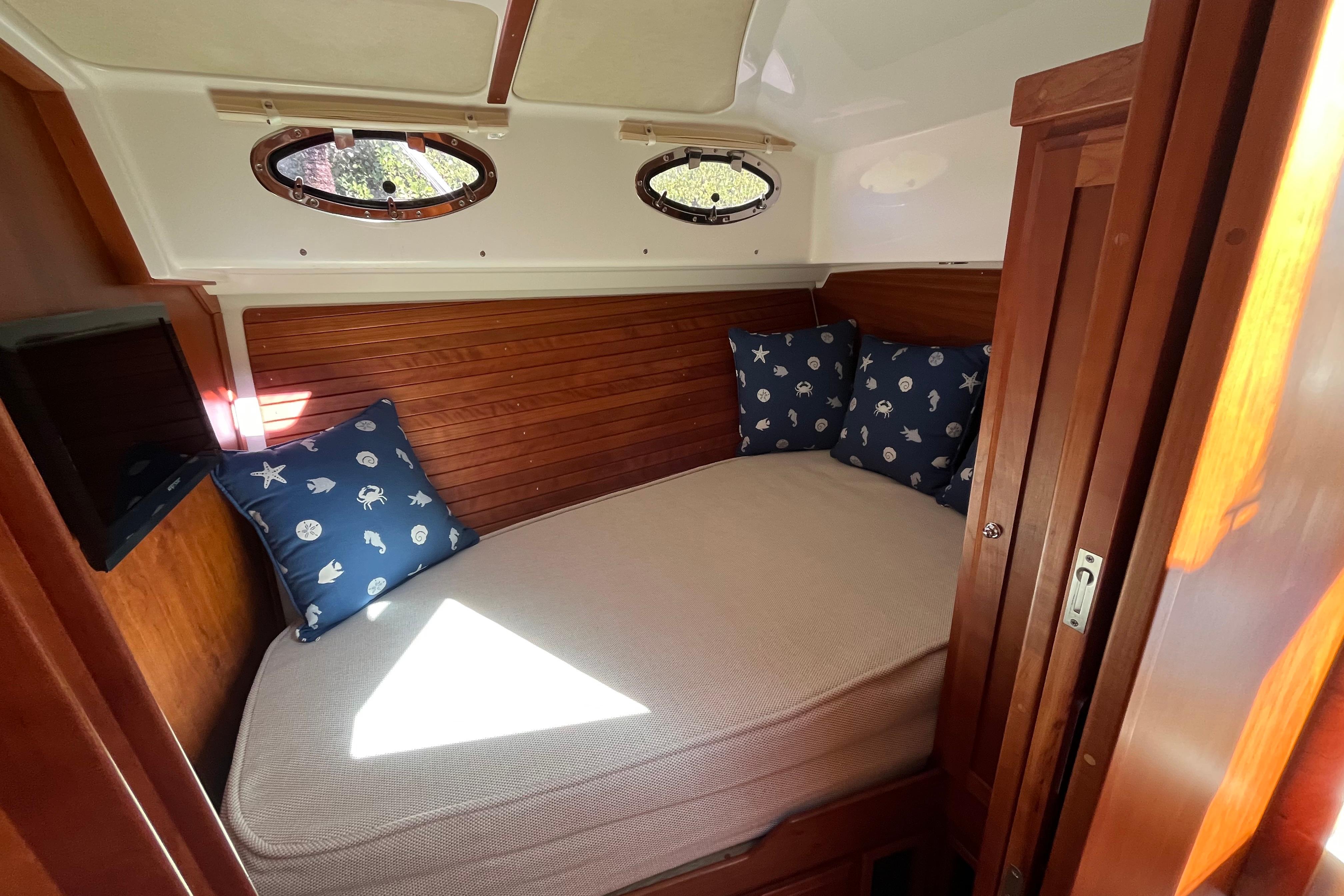 Cozy cabin interior of 2017 Back Cove 37 with nautical-themed pillows and wooden accents.