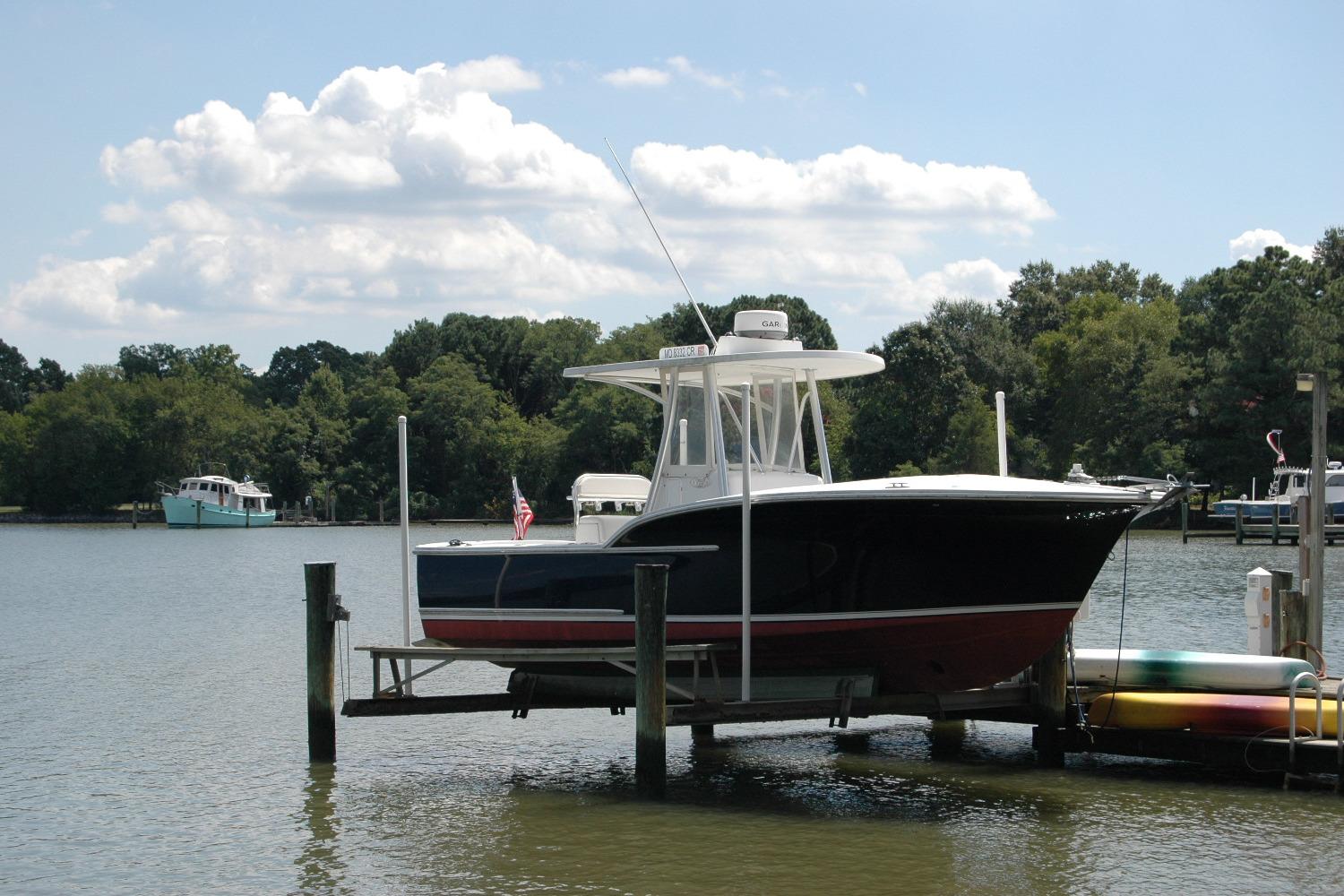 2013 Composite Yacht 26 on lift by serene lake with trees and boats.