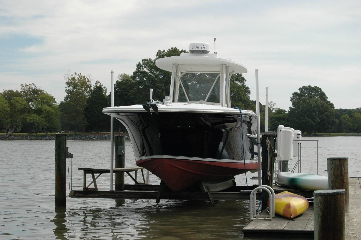2013 Composite Yacht 26 on lift at dock, surrounded by trees and water.