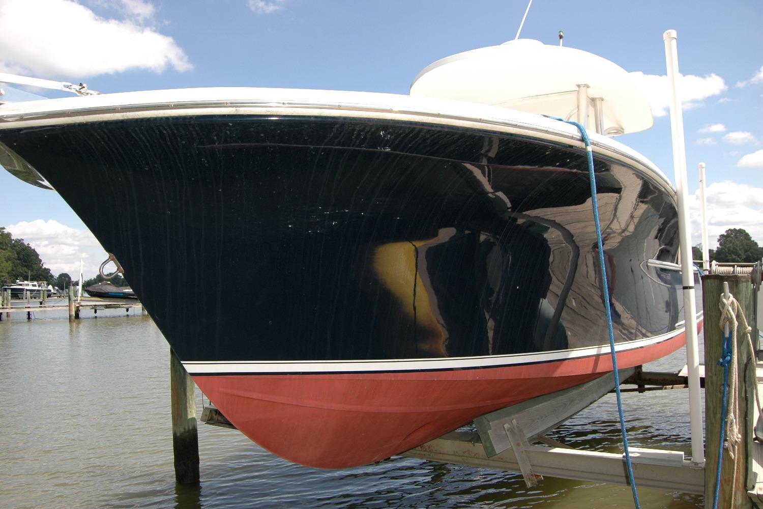 2013 Composite Yacht 26 on lift, showcasing sleek black hull and red bottom paint.