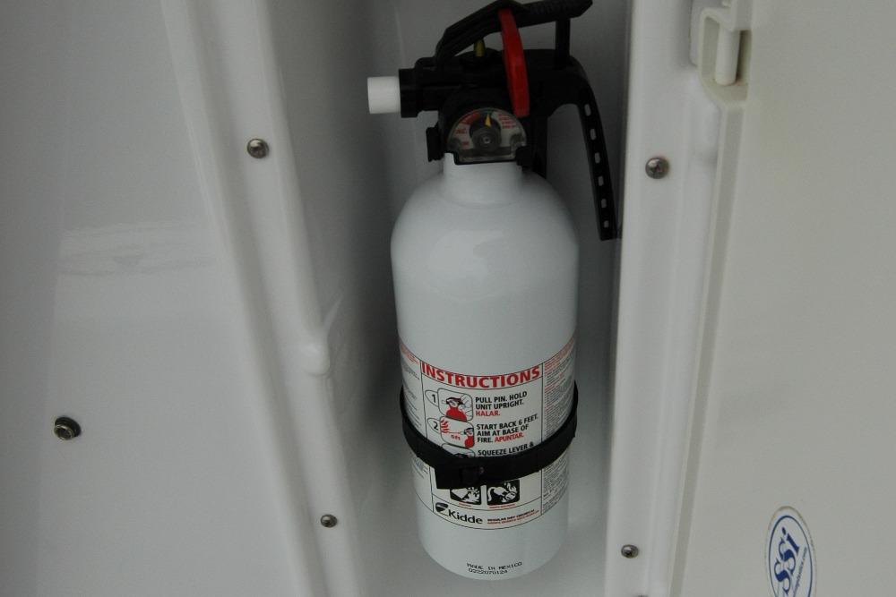 Fire extinguisher mounted on 2013 Composite Yacht 26 interior wall.