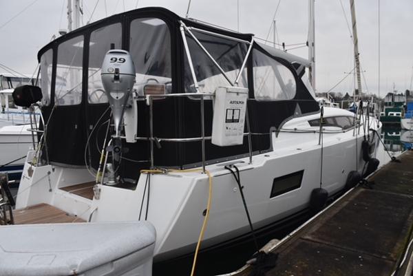 2016 Jeanneau 54 yacht docked, featuring a covered cockpit and outboard motor.