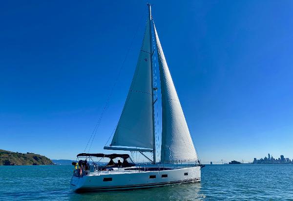 2016 Jeanneau 54 sailboat on calm waters with city skyline in background.