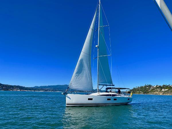 2016 Jeanneau 54 sailboat on calm blue waters under clear skies.