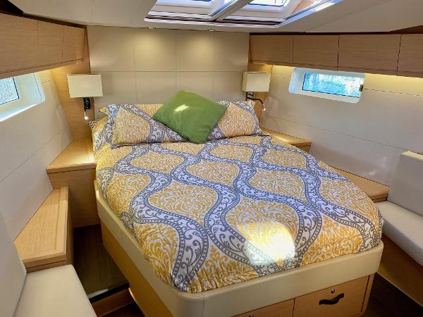 Luxurious cabin interior of a 2016 Jeanneau 54 yacht with elegant bedding and natural light.