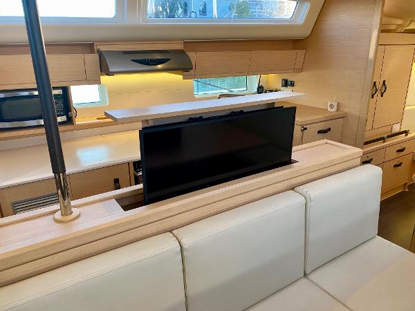 Interior of 2016 Jeanneau 54 yacht with modern kitchen and pop-up TV.