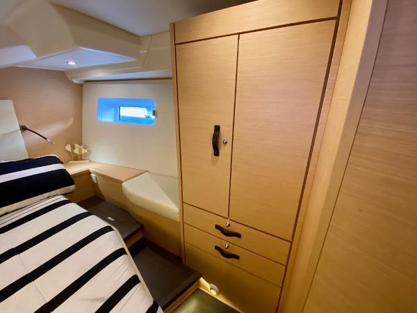 Luxurious cabin interior of 2016 Jeanneau 54 yacht with striped bedding and wooden cabinetry.