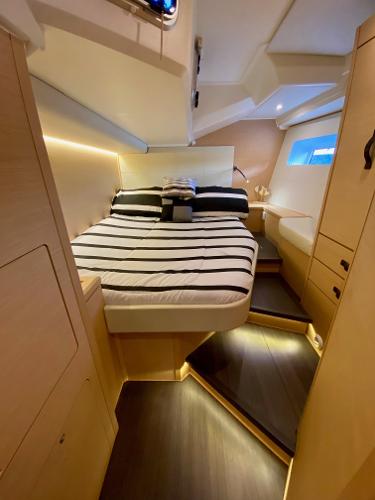 Luxurious cabin interior of 2016 Jeanneau 54 yacht with striped bedding and ambient lighting.