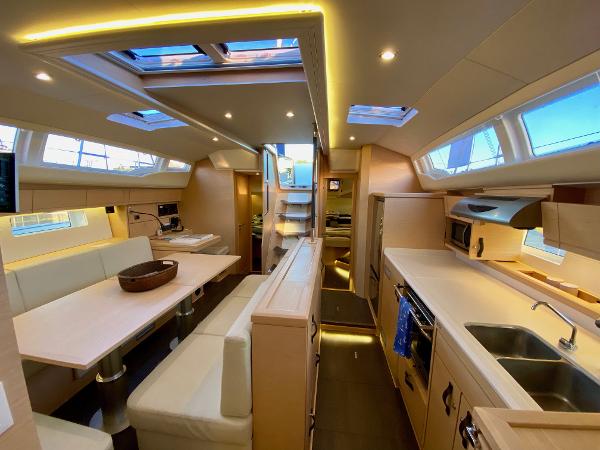 Luxurious interior of a 2016 Jeanneau 54 yacht, featuring modern kitchen and dining area.