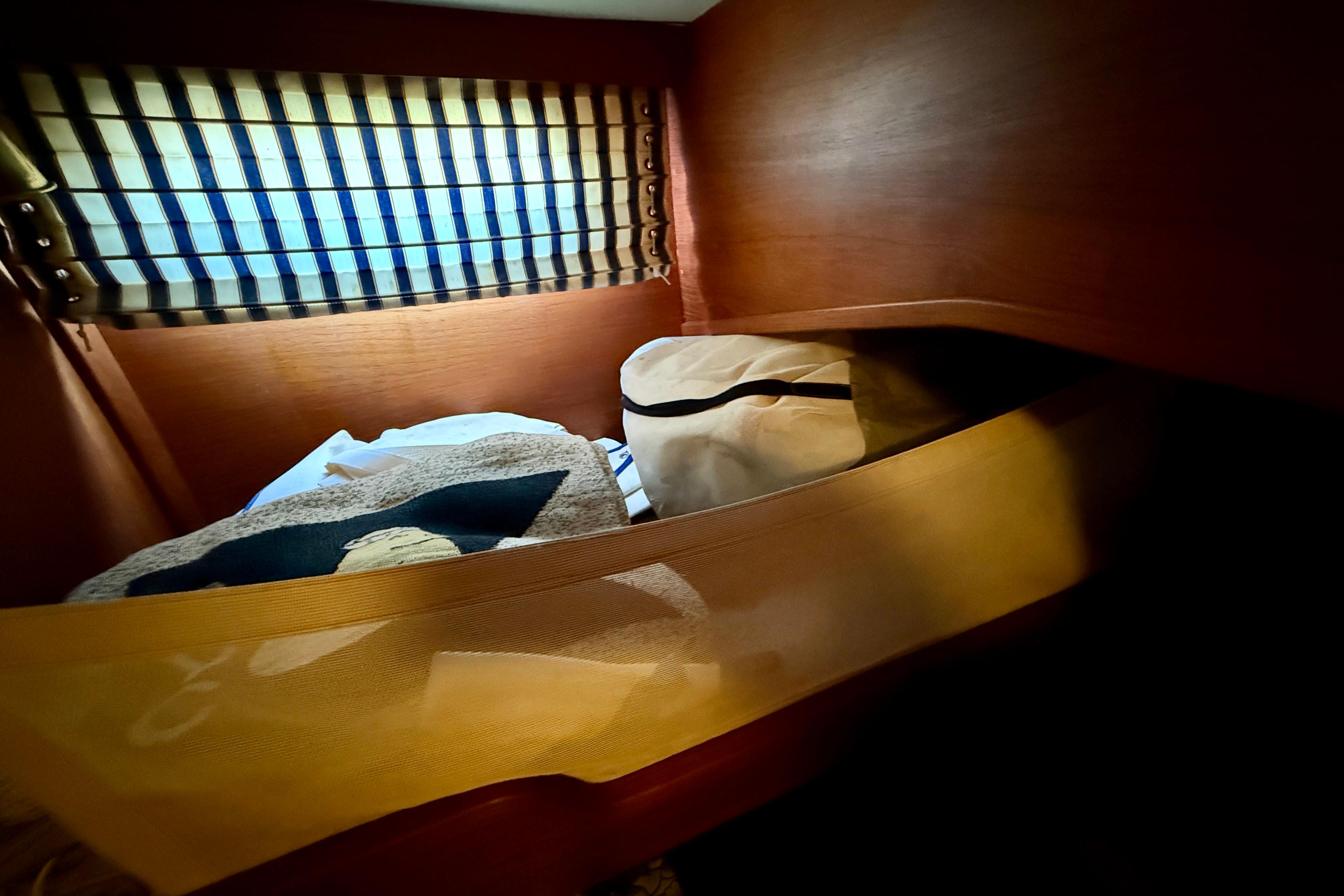 Cozy cabin interior of 1986 Nauticat 43 sailboat with striped window curtain.