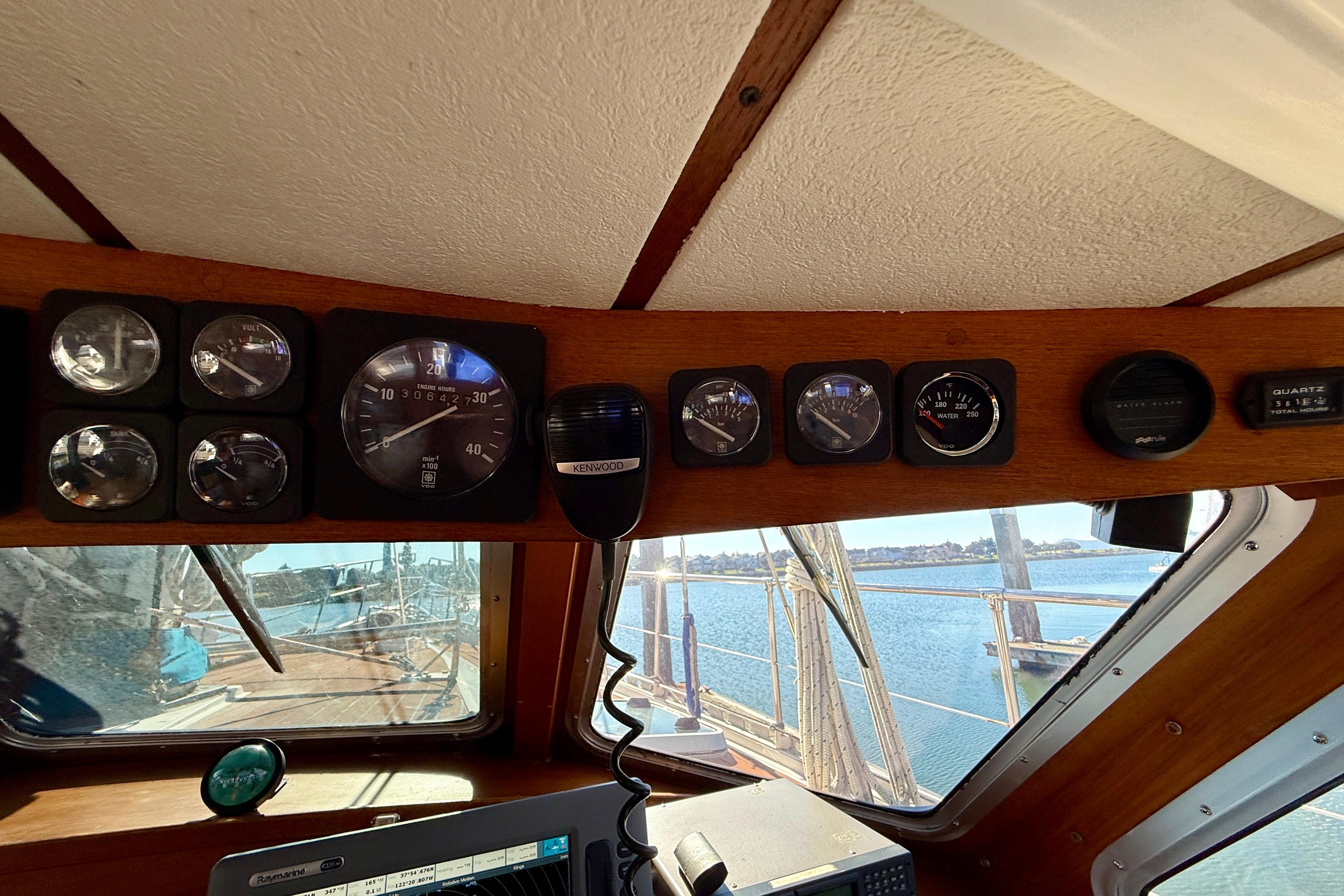 1986 Nauticat 43 cockpit with gauges and Kenwood radio, overlooking water.