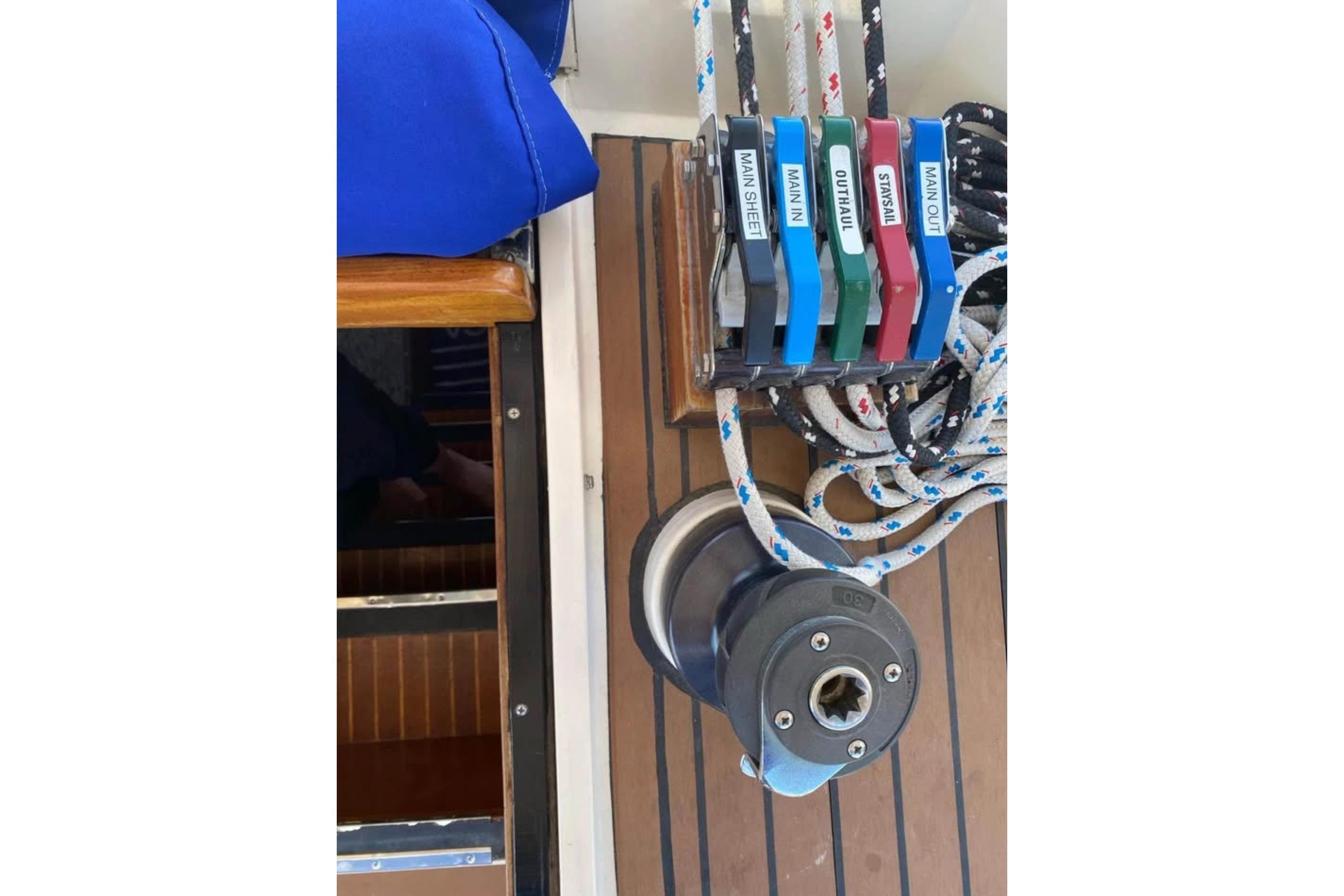 Sailing controls on a 1986 Nauticat 43 yacht, featuring labeled ropes and winch.
