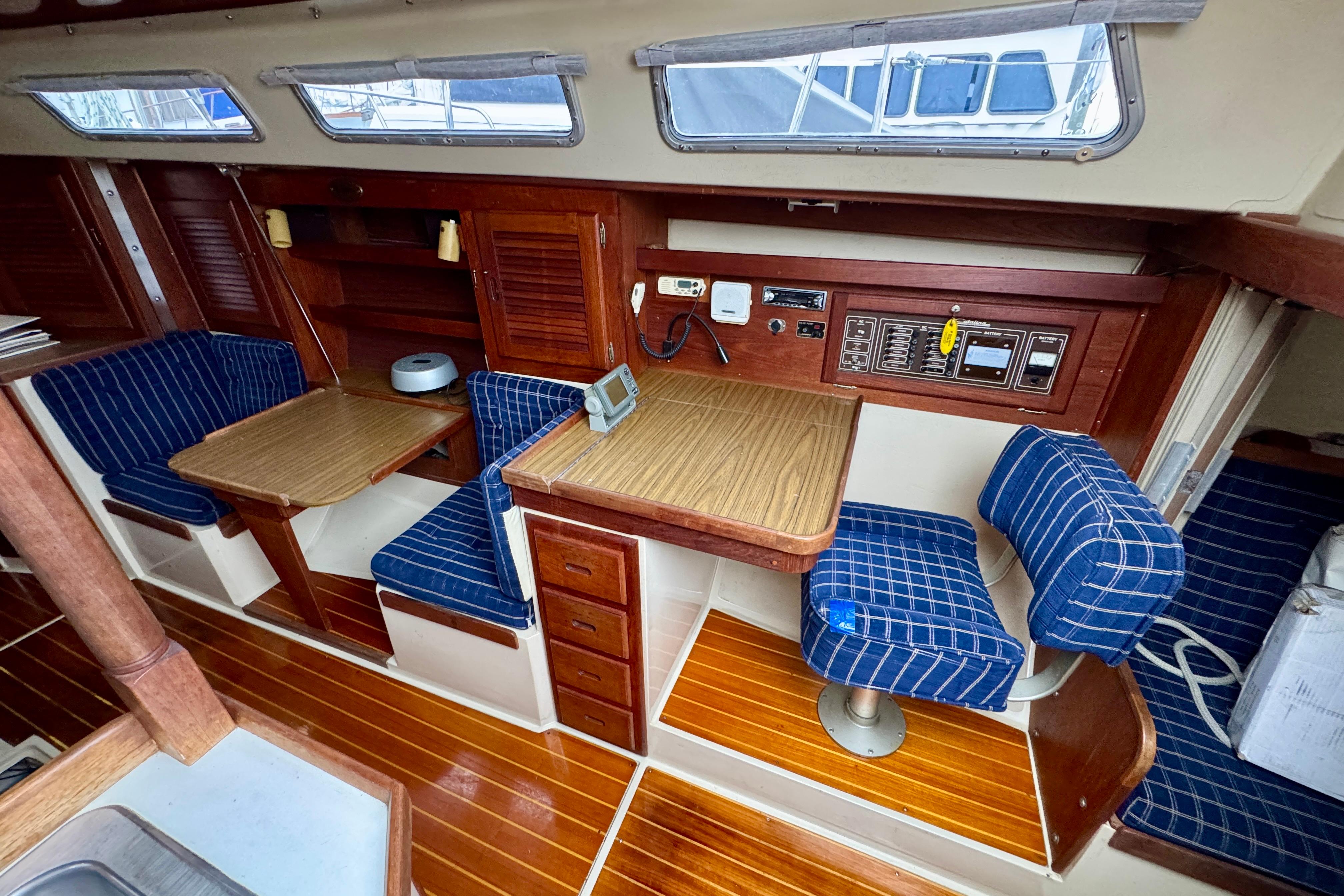 1986 Catalina 36 yacht interior with wood finish, blue plaid seating, and navigation station.