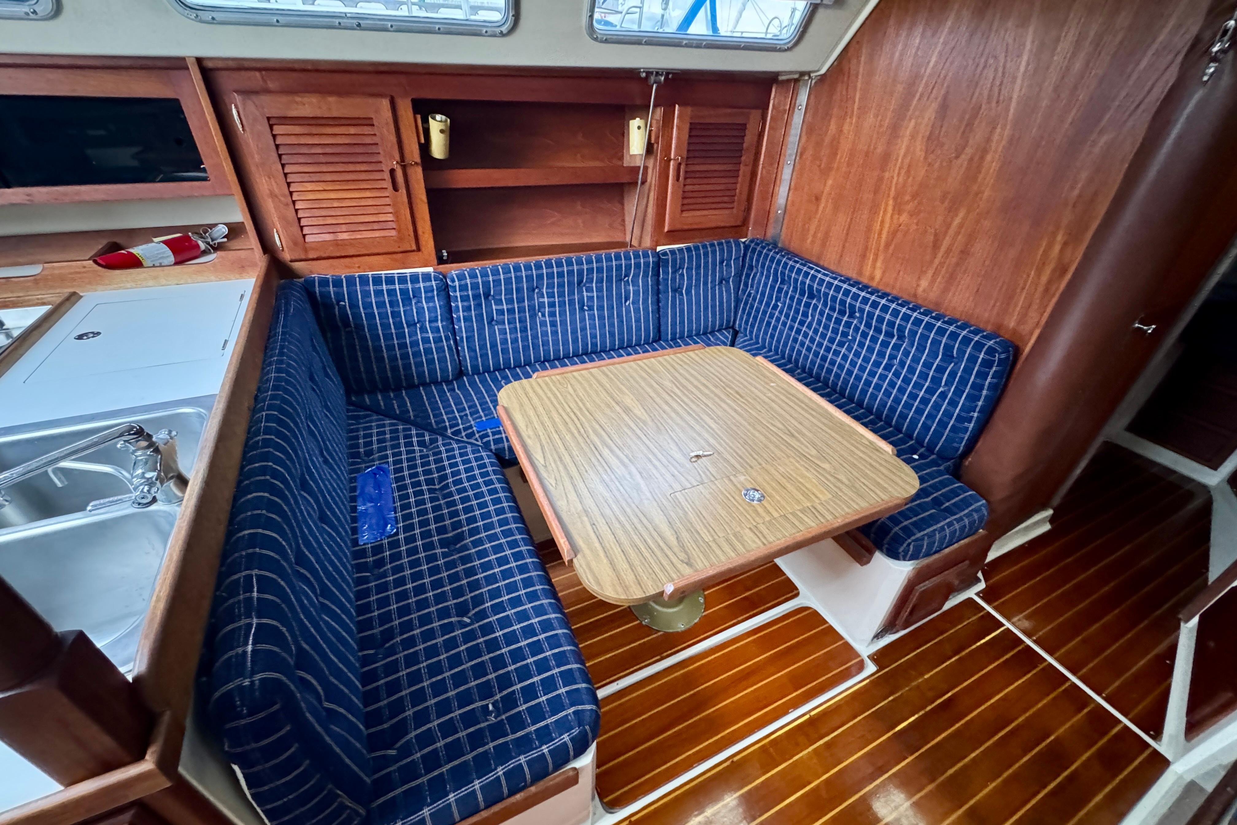Cozy interior of 1986 Catalina 36 sailboat with blue-striped seating and wooden table.