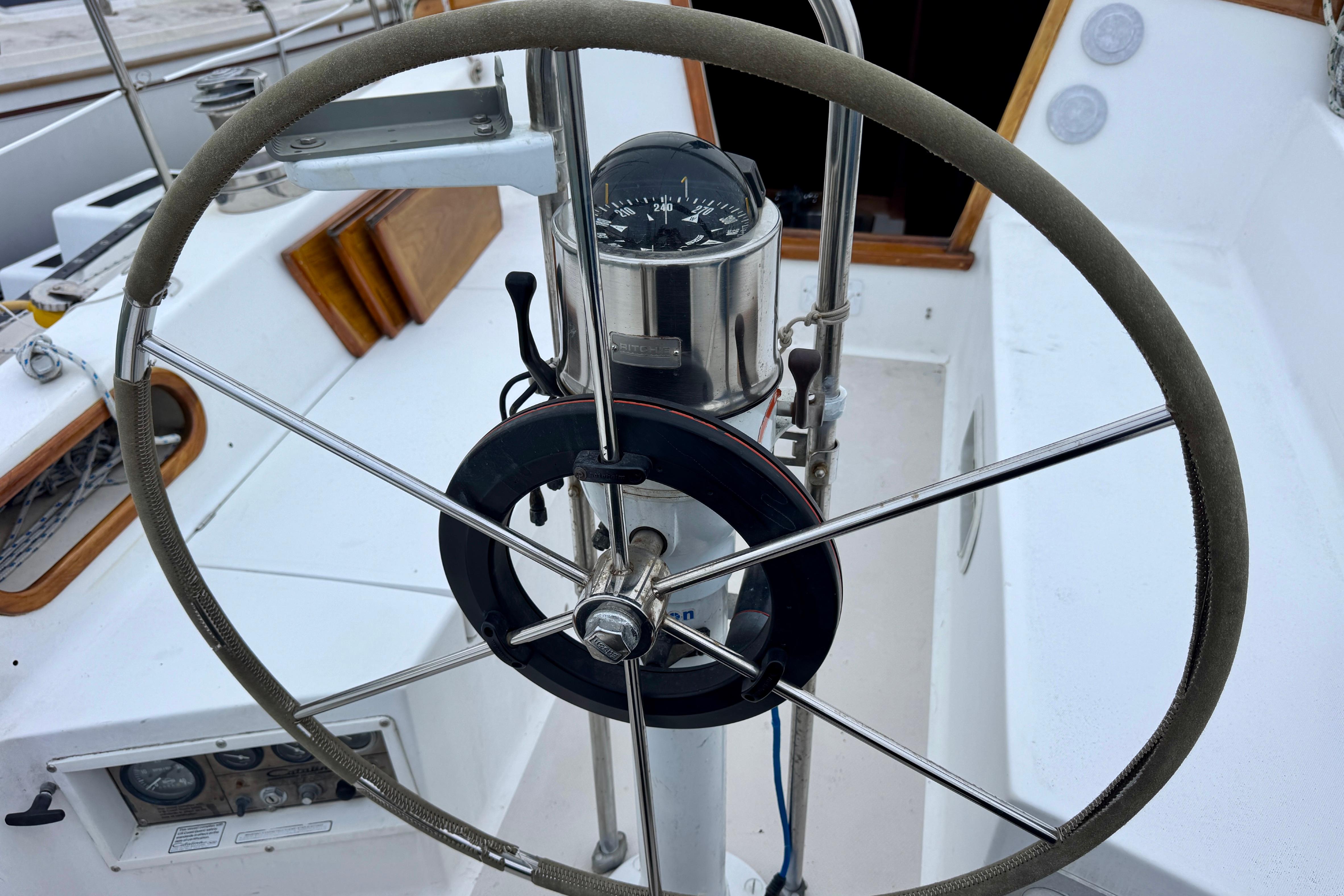 Steering wheel of a 1986 Catalina 36 sailboat with compass and cockpit view.