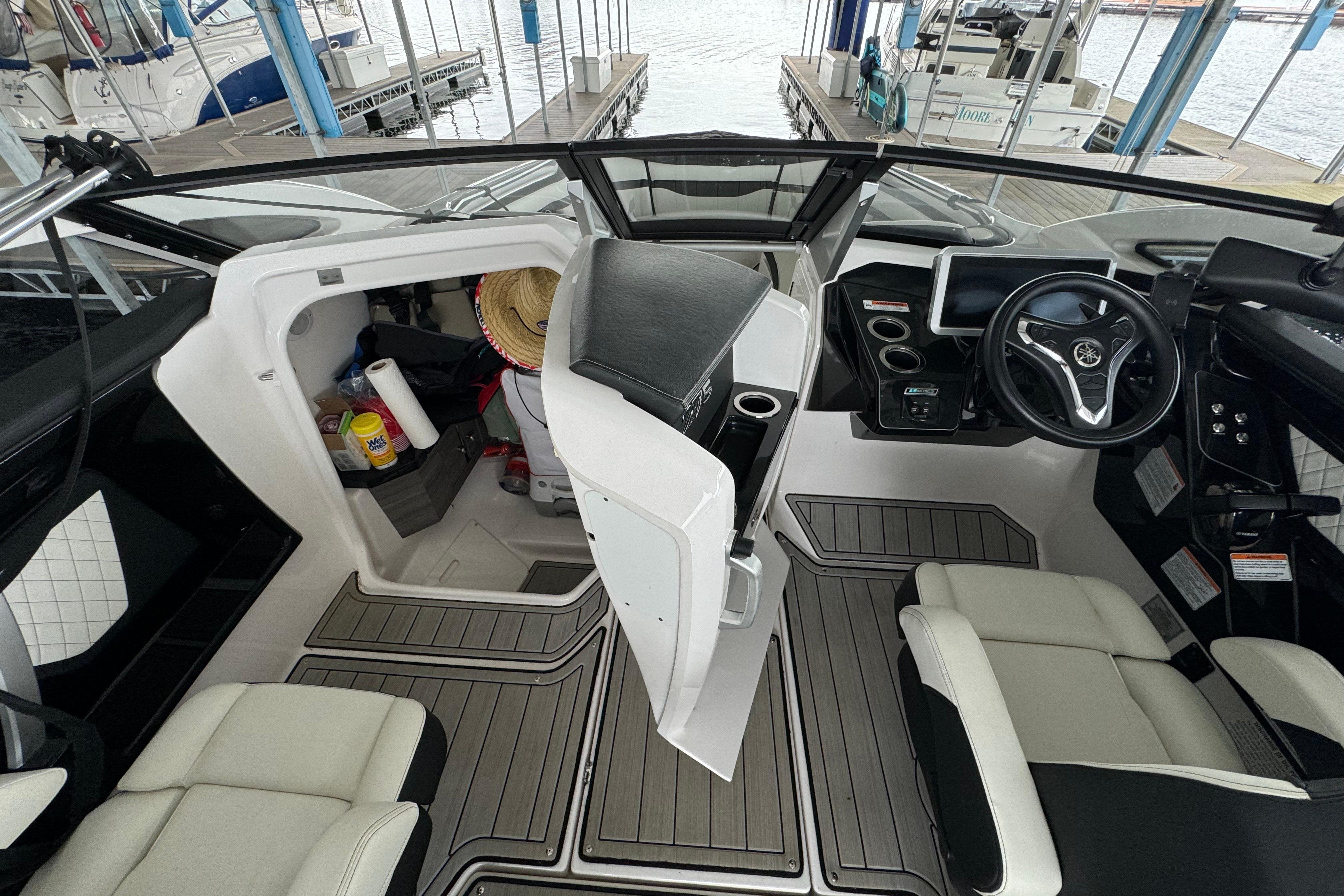 2024 Yamaha Boats 275SD interior with helm, seating, and storage area.