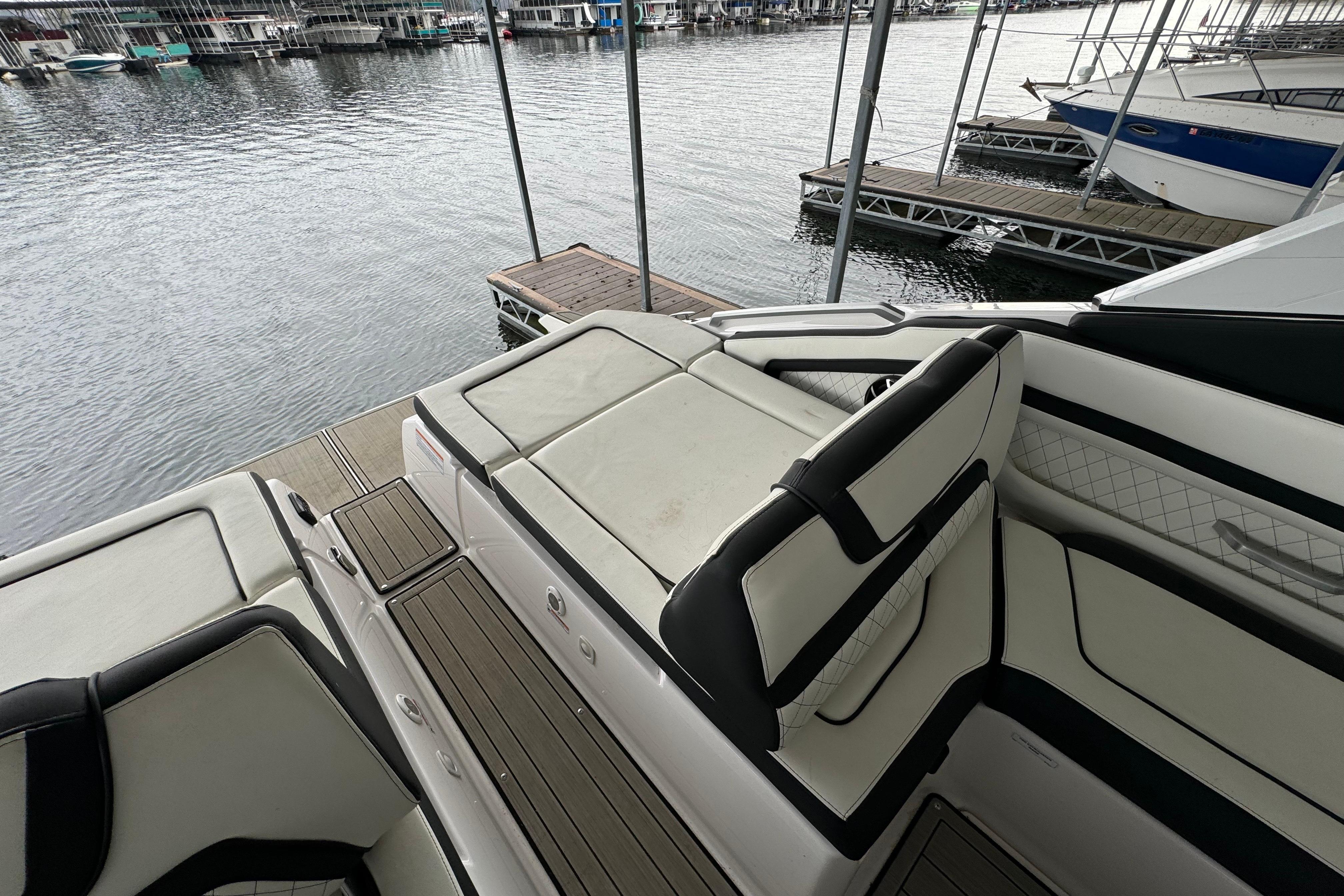 2024 Yamaha Boats 275SD interior with luxurious seating at a marina dock.