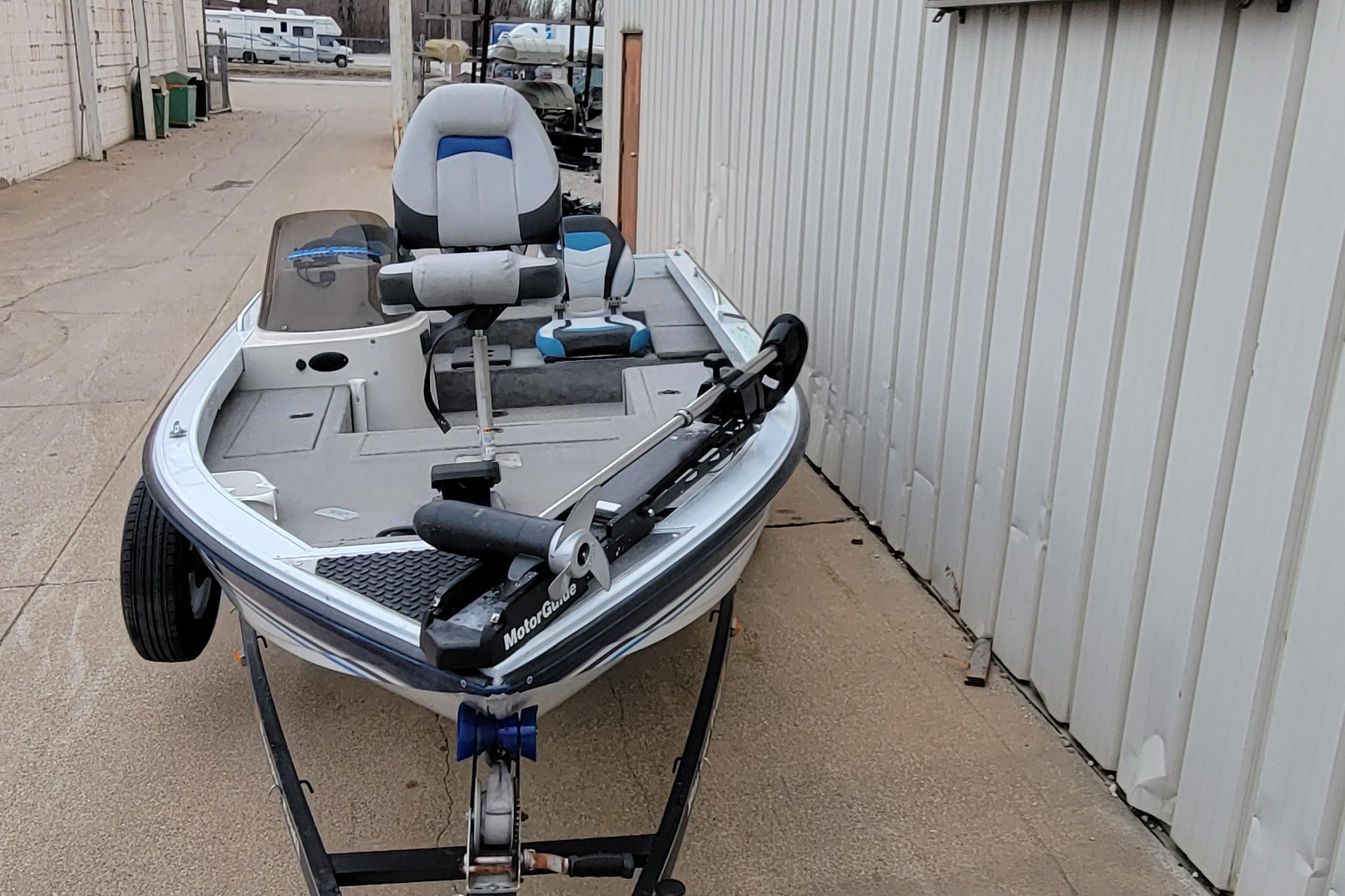 1999 Ranger 107 Cherokee boat on trailer, parked beside a building.